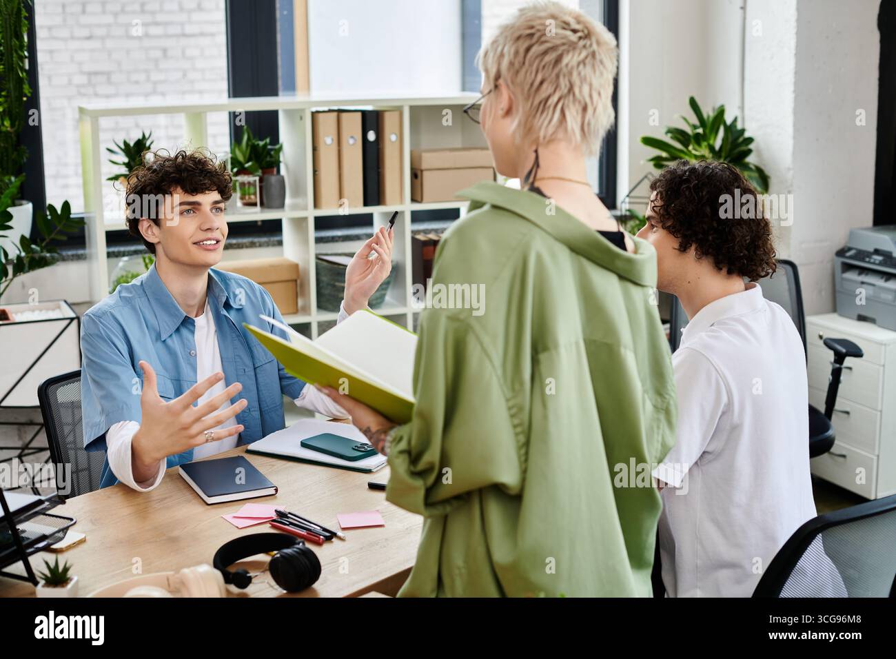 Dynamic interaction between young professionals discussing ideas at a stylish office workspace. Stock Photo