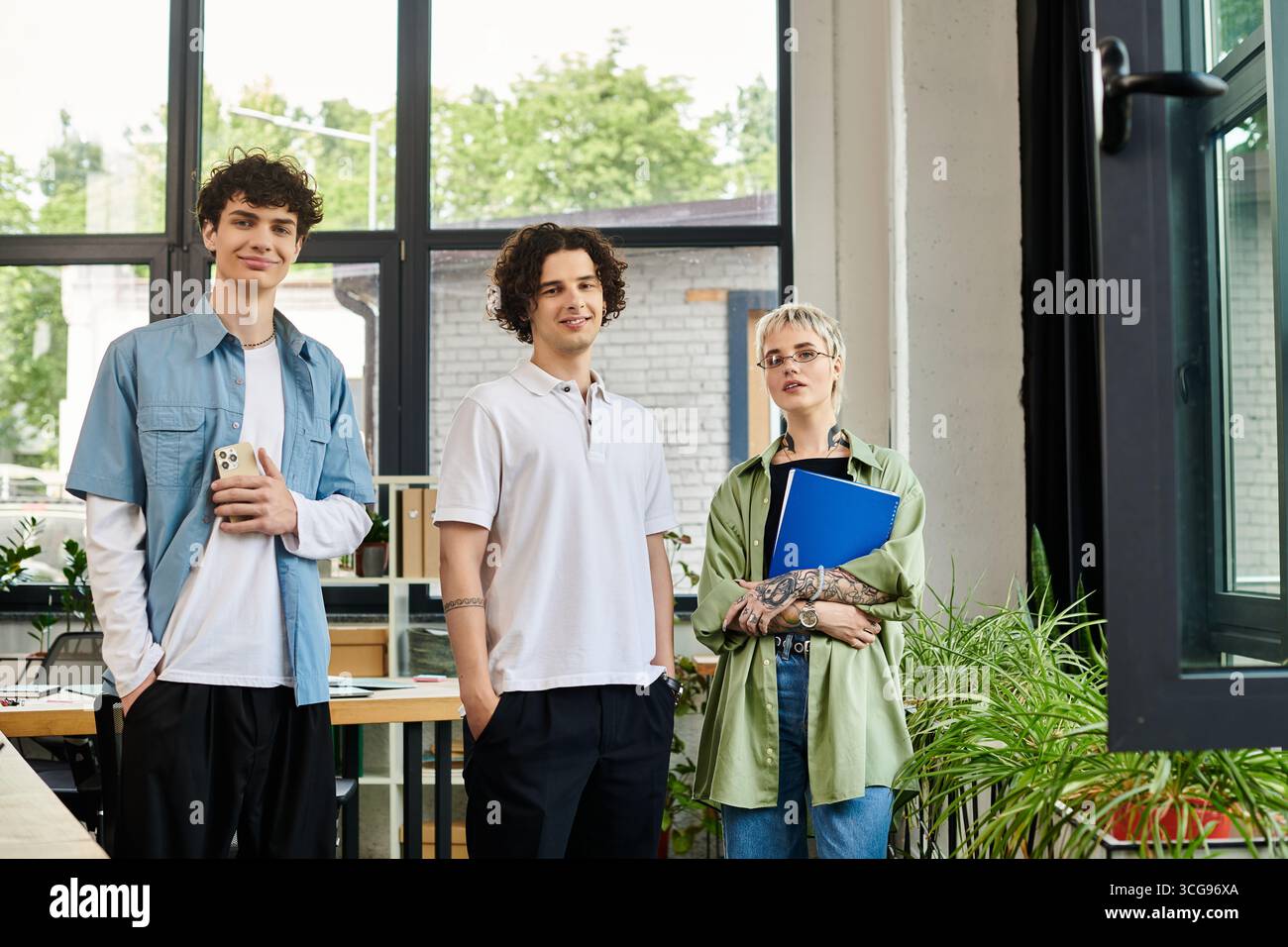 Three young people are collaborating in a bright office. Stock Photo