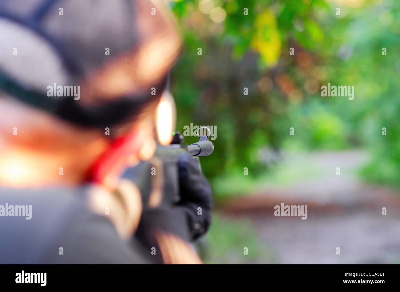 Sniper aims rifle for a shot. Optical sight on weapon close-up. Concept of danger, target, terrorism. Blurred background. Stock Photo
