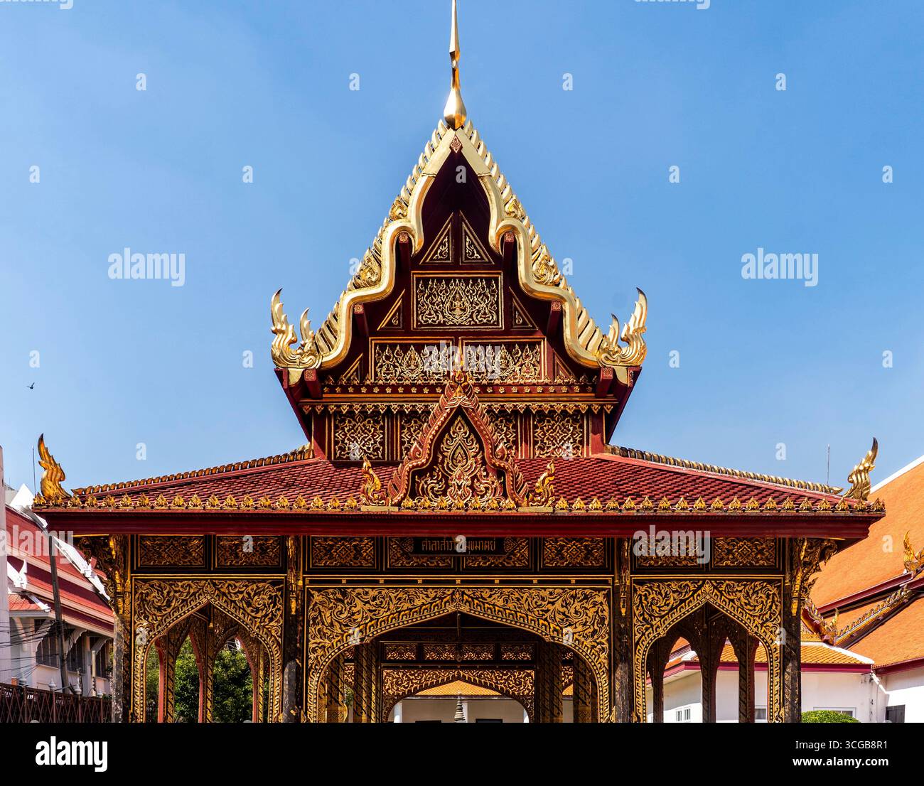 Ornate traditional Thai architecture with intricate gold detailing and a blue sky background Stock Photo