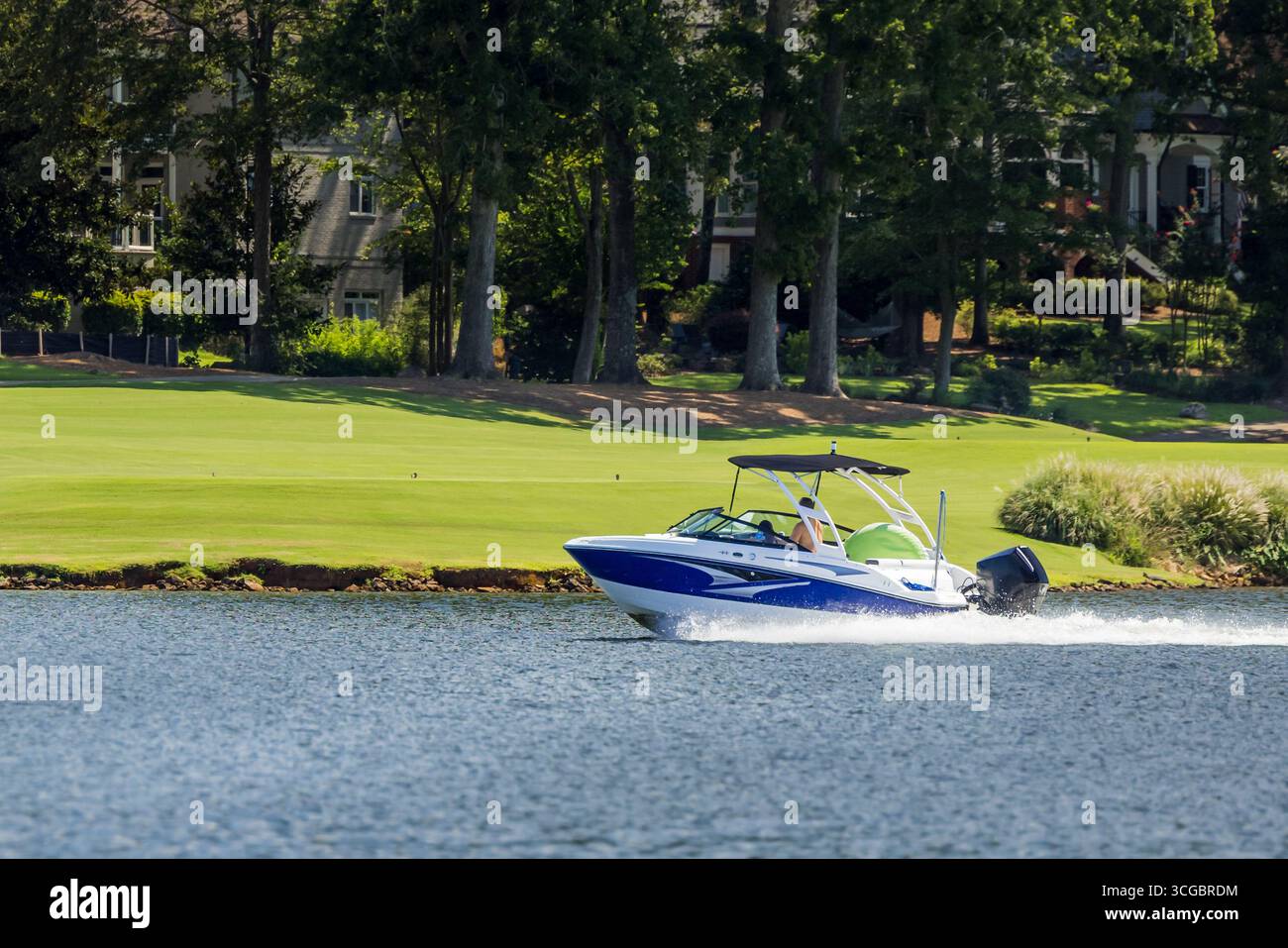Boaters on wakeboard wake ski boat enjoying summer day on freshwater lake. Stock Photo