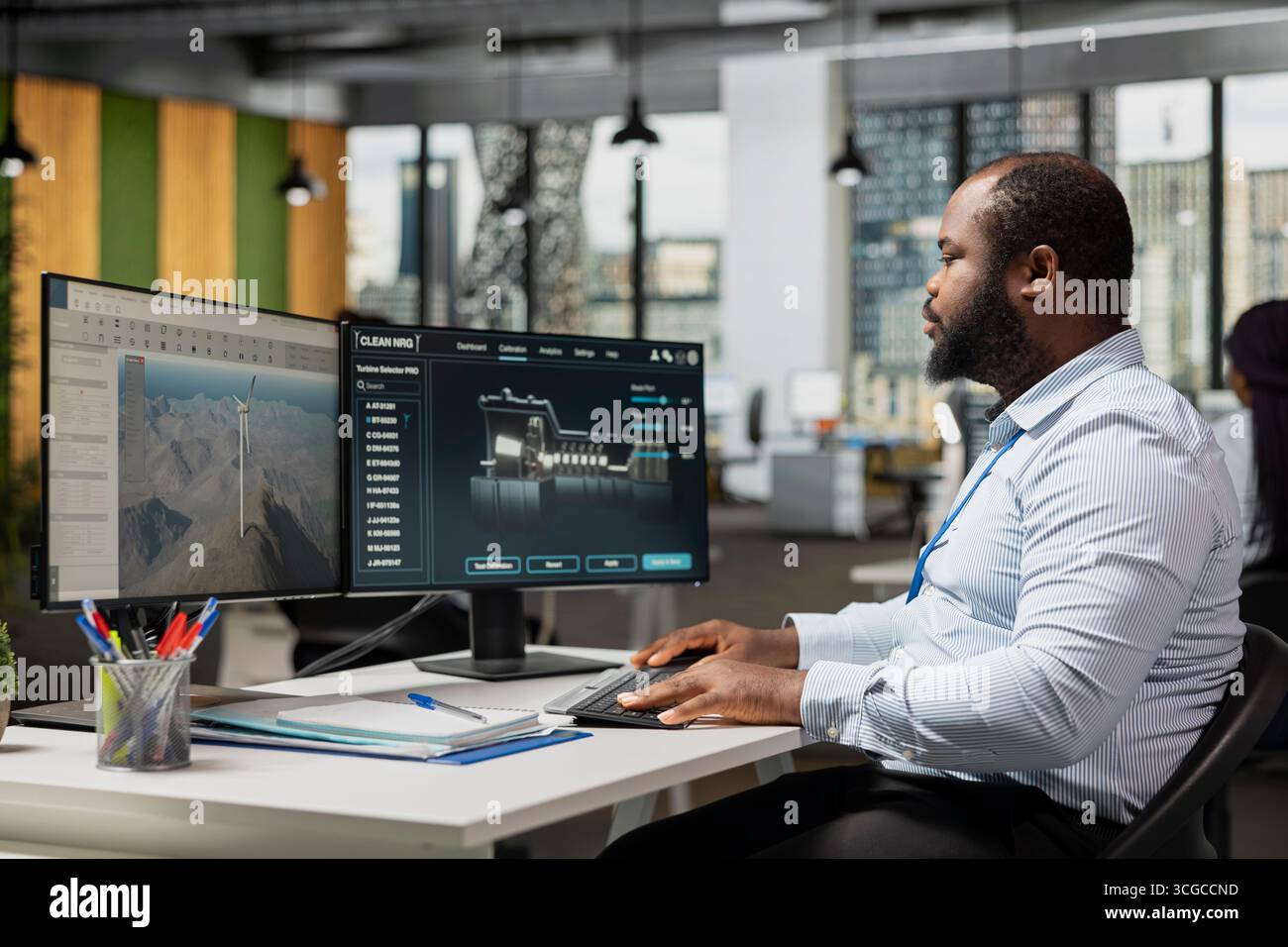 Engineer in office uses dual monitor setup to analyze turbine mechanics ...