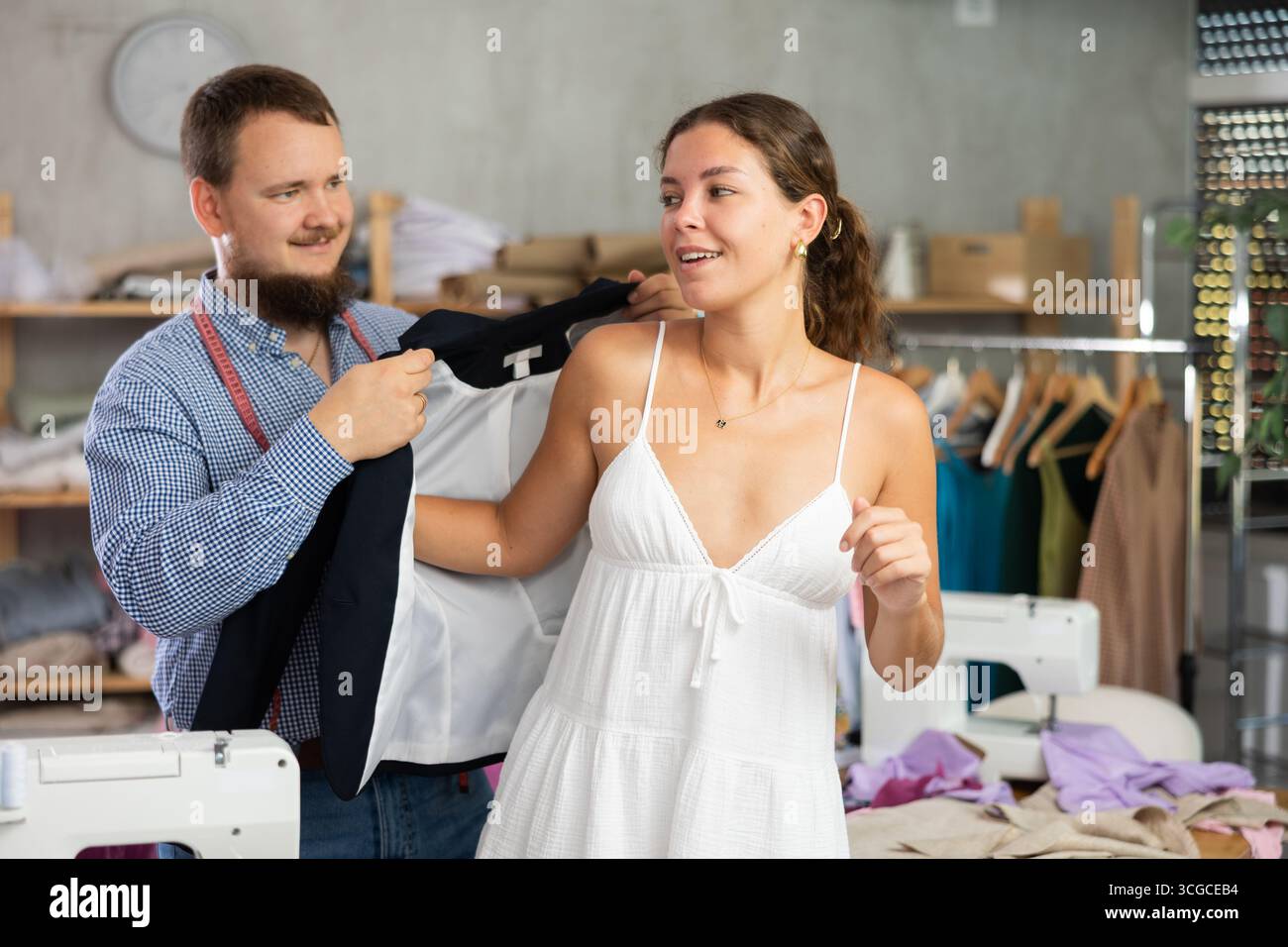 Female client trying on custom blazer with tailor in workshop Stock Photo
