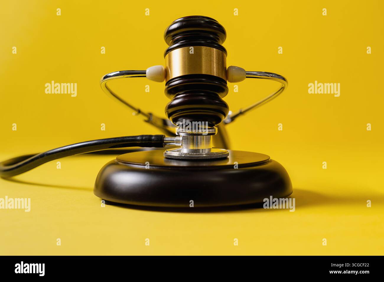 Gavel with stethoscope wrapped around on yellow background. Legal and medical. Stock Photo