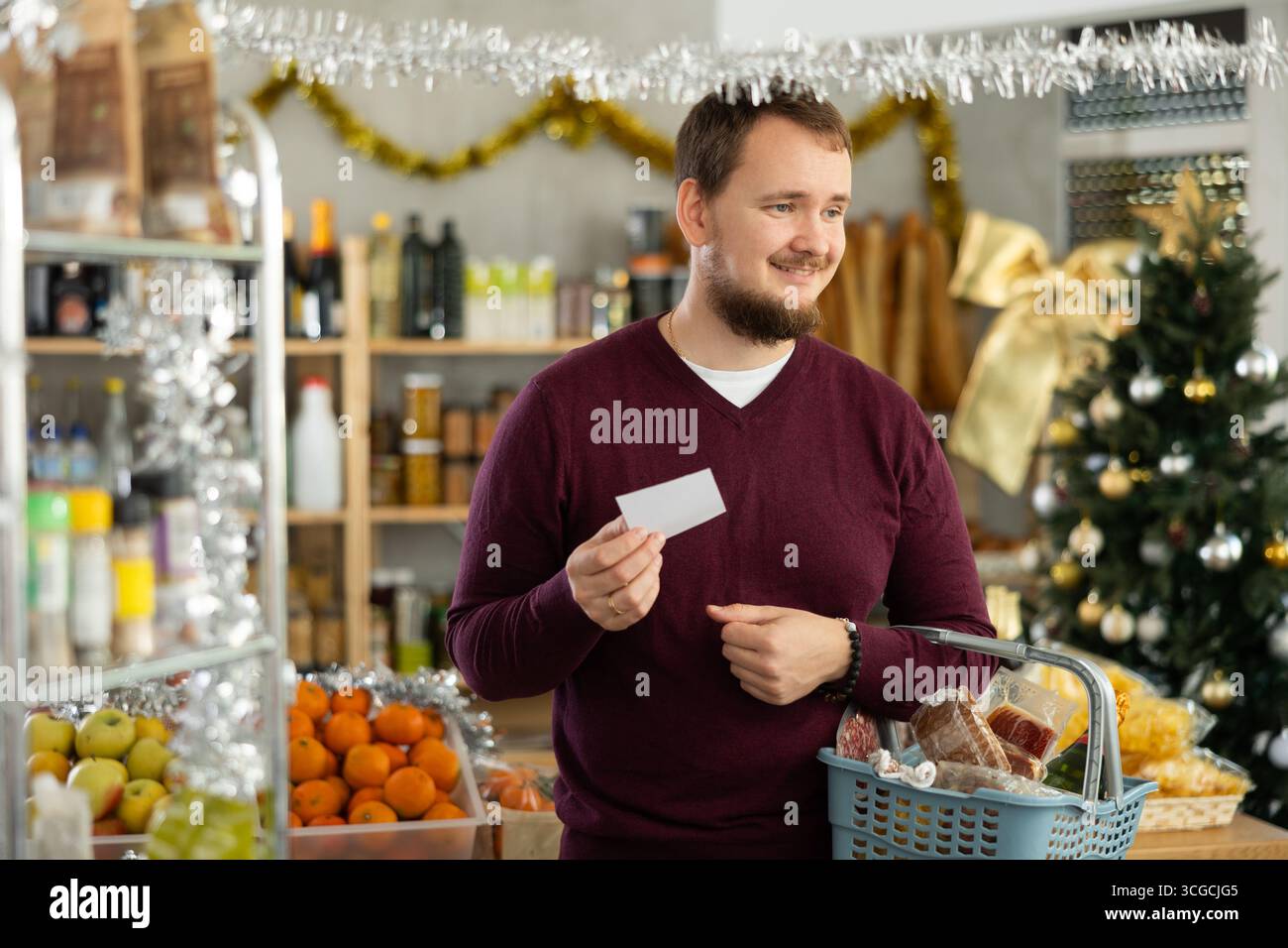 Young man shopping with list for Christmas snacks in store Stock Photo