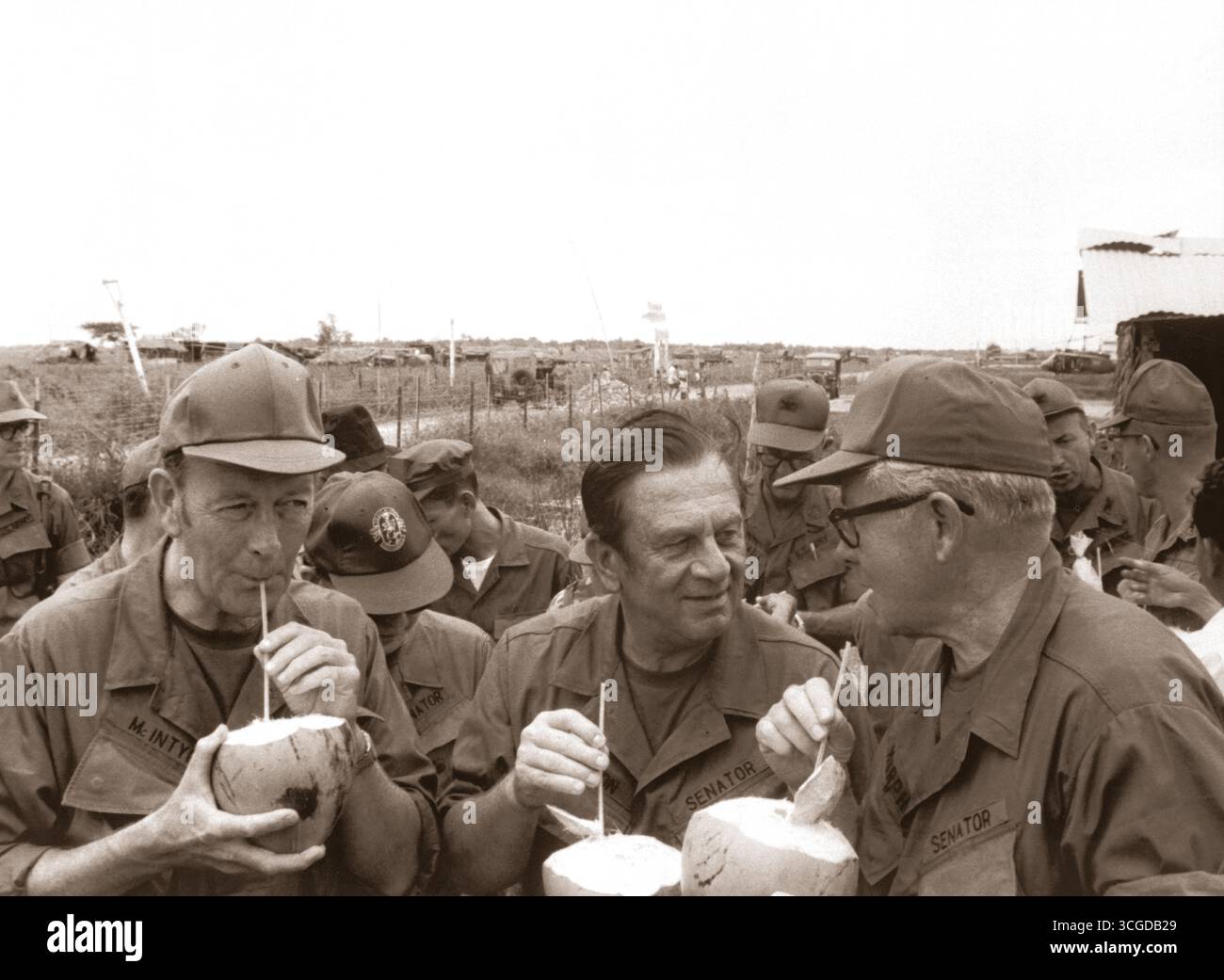 Pausing for refreshments during their visit to Huu Thanh, a recently pacified village, three U.S. Senators on President Nixon's fact-finding committee drink from local coconuts.  Sen. Thomas J. McIntyre, Sen. Howard Cannon, and Sen. George Murphy.  Circa 1970. Stock Photo