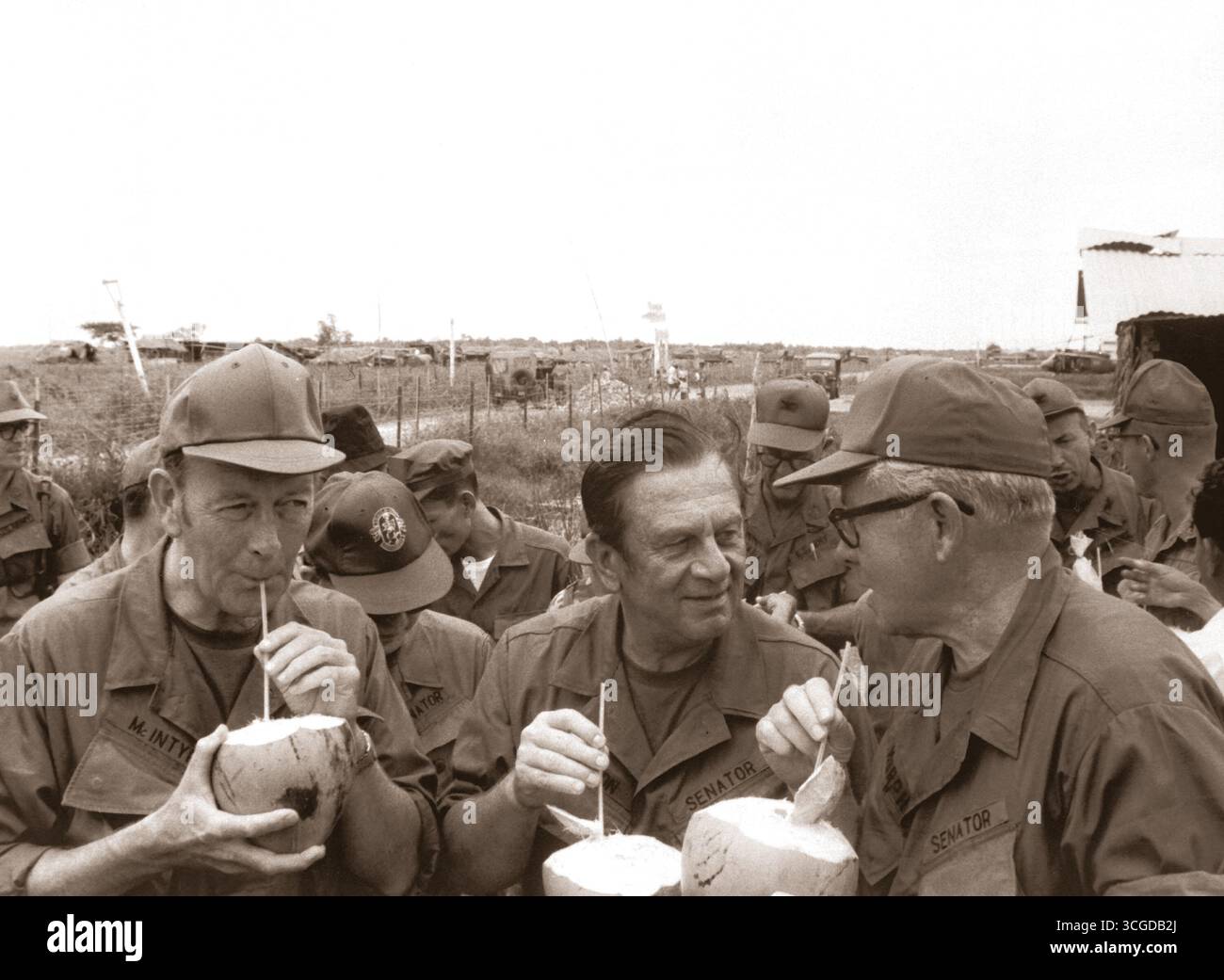 Pausing for refreshments during their visit to Huu Thanh, a recently pacified village, three U.S. Senators on President Nixon's fact-finding committee drink from local coconuts.  Sen. Thomas J. McIntyre, Sen. Howard Cannon, and Sen. George Murphy.  Circa 1970. Stock Photo