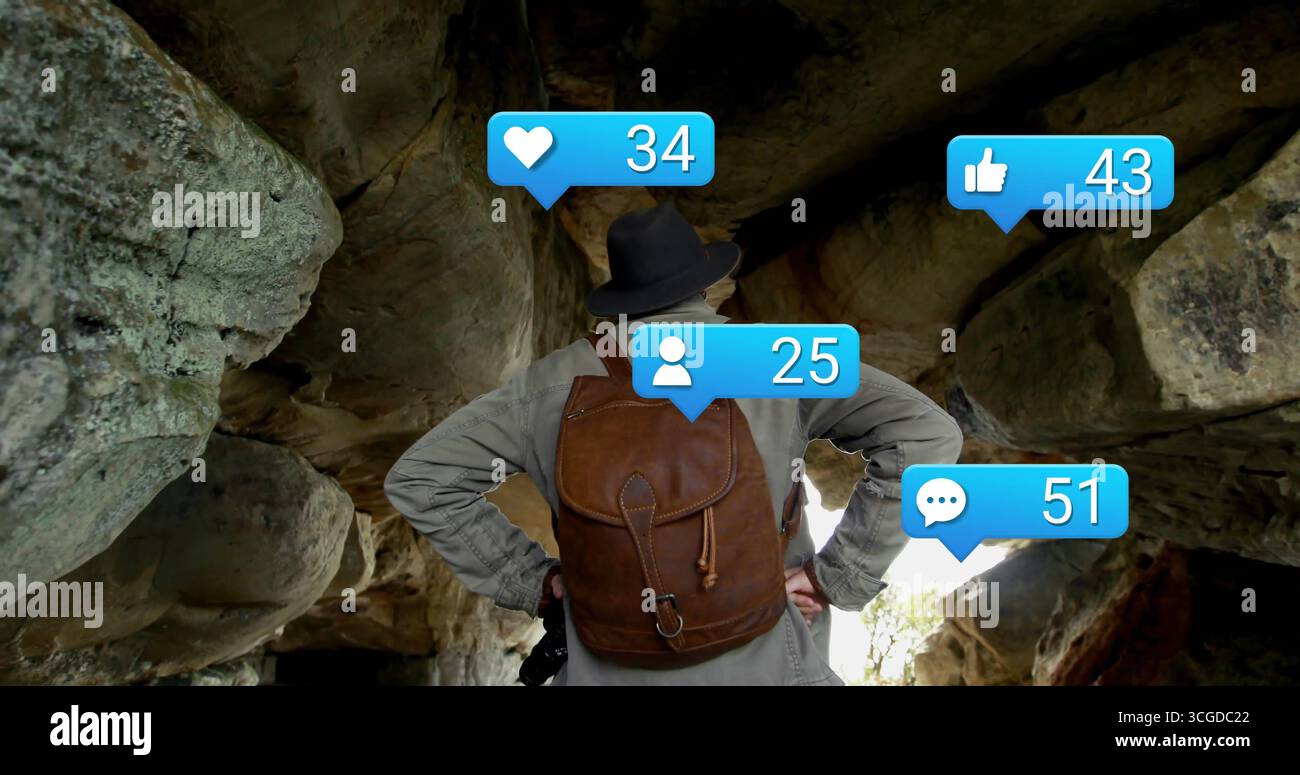 Standing hiker wearing brimmed hat and leather backpack in rock shelter ...