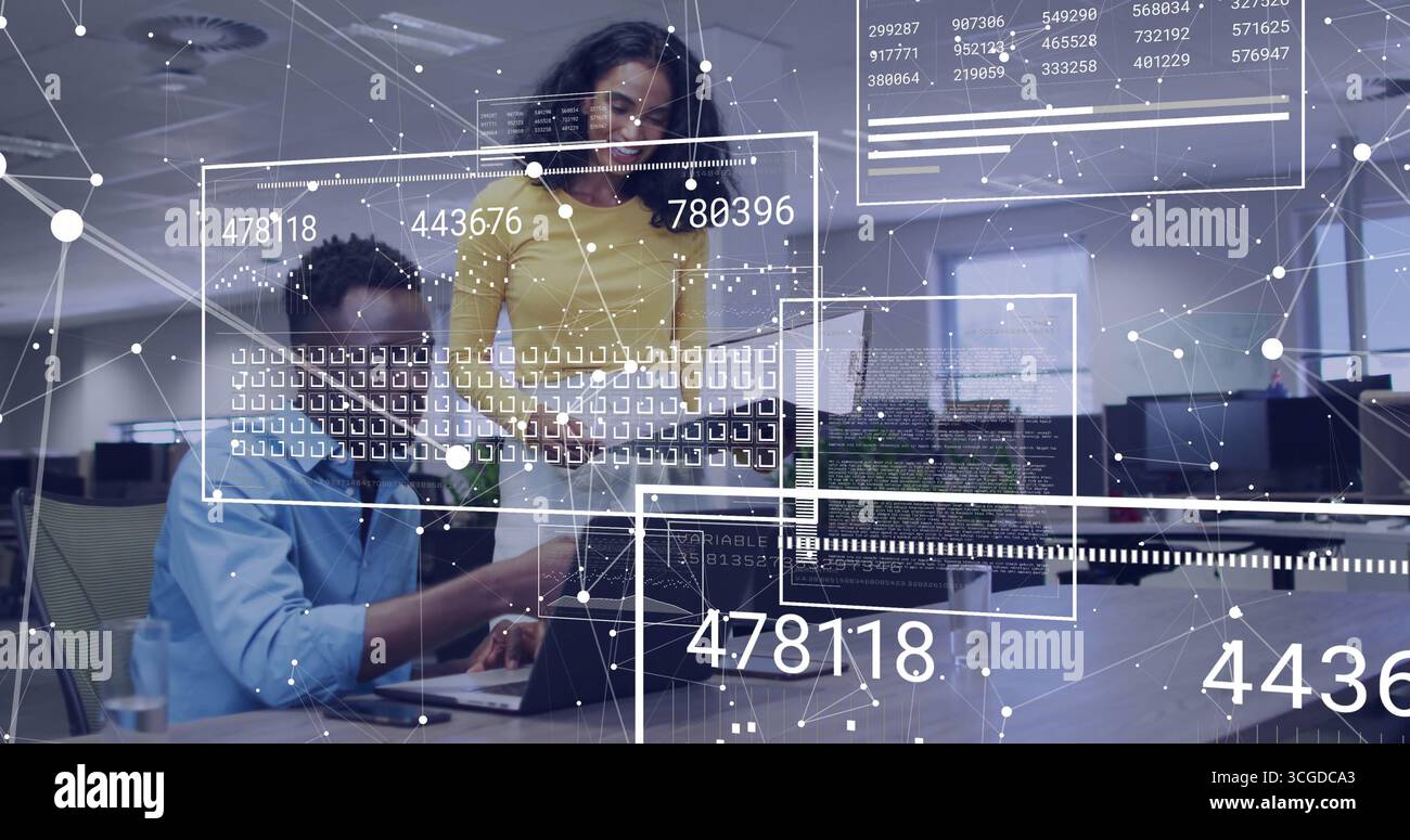 Collaborating technology experts examining network data overlays on laptop in open-plan office Stock Photo