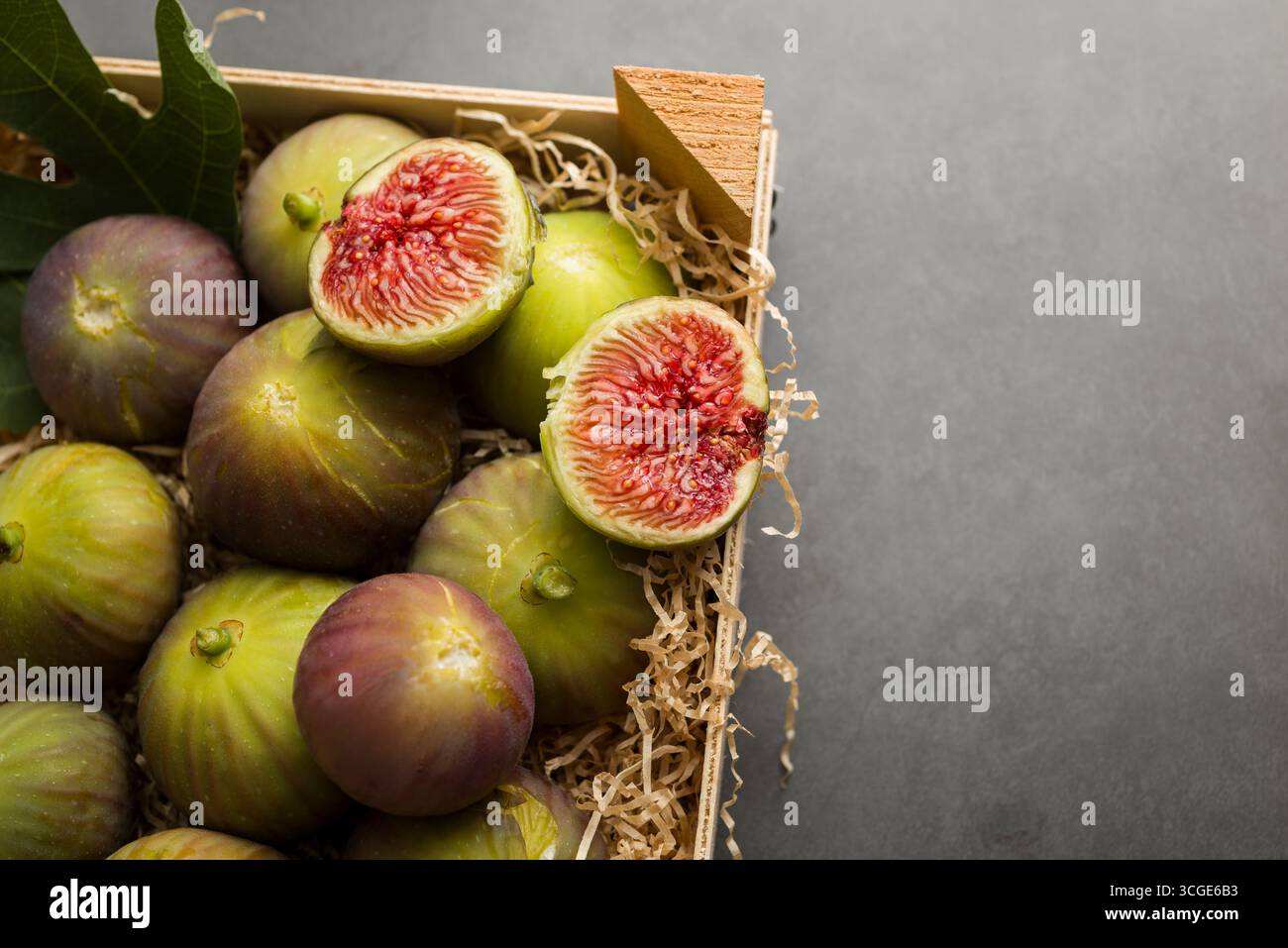 Fresh figs placed into wooden box on dark table. Stock Photo