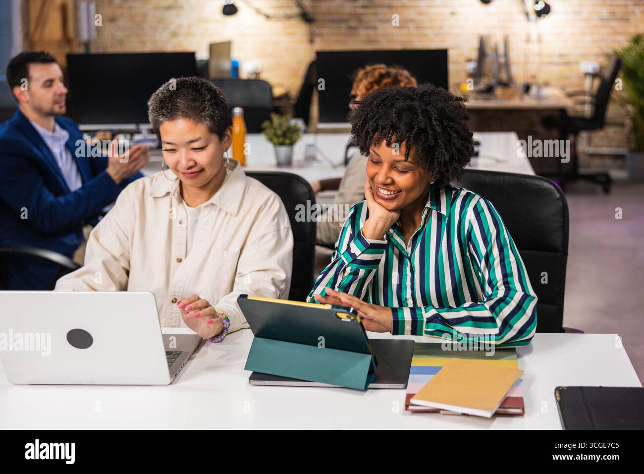 Multi ethnic team collaborating on project using laptop and tablet in office Stock Photo