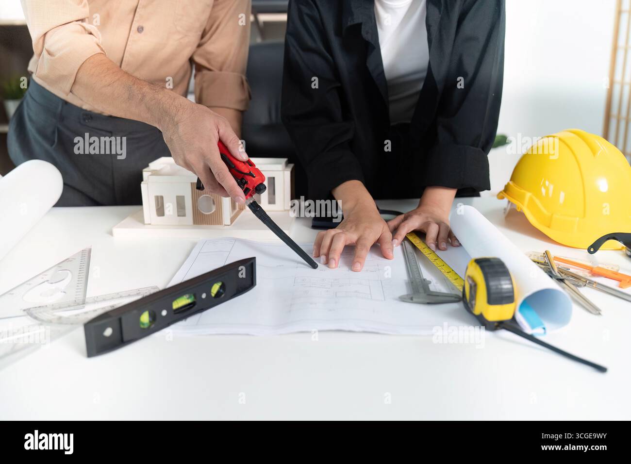Construction Collaboration. Architects reviewing blueprints together at a modern workspace. Stock Photo