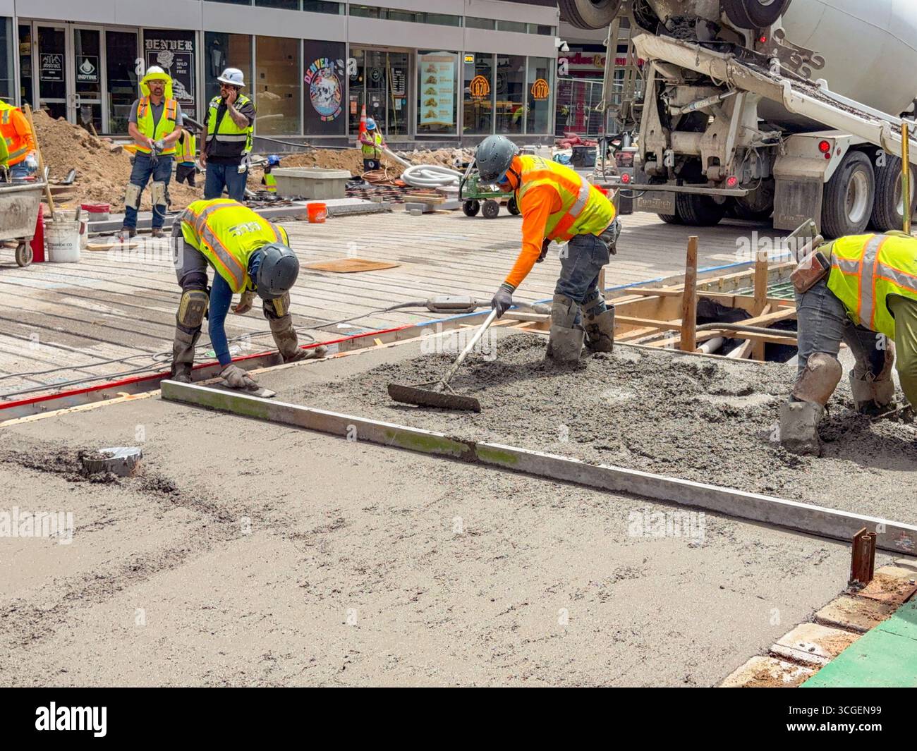 Denver, Colorado, USA - 4 June 2025: Construction workers levelling new concrete on a road in the city centre. - Smartphone Captured Stock Image