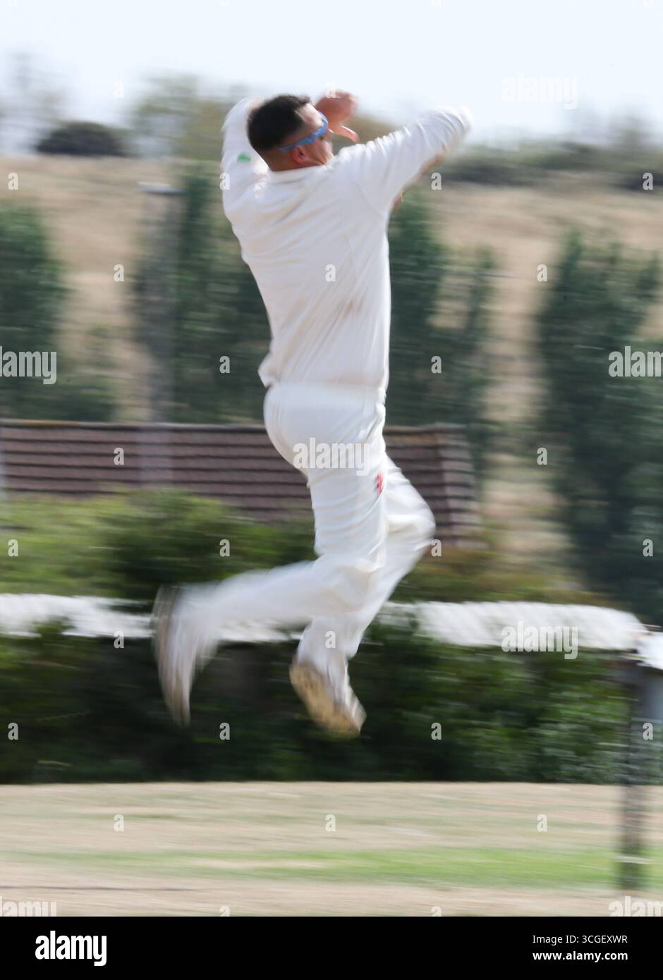 A bowler in action with a side on view at a cricket game Stock Photo