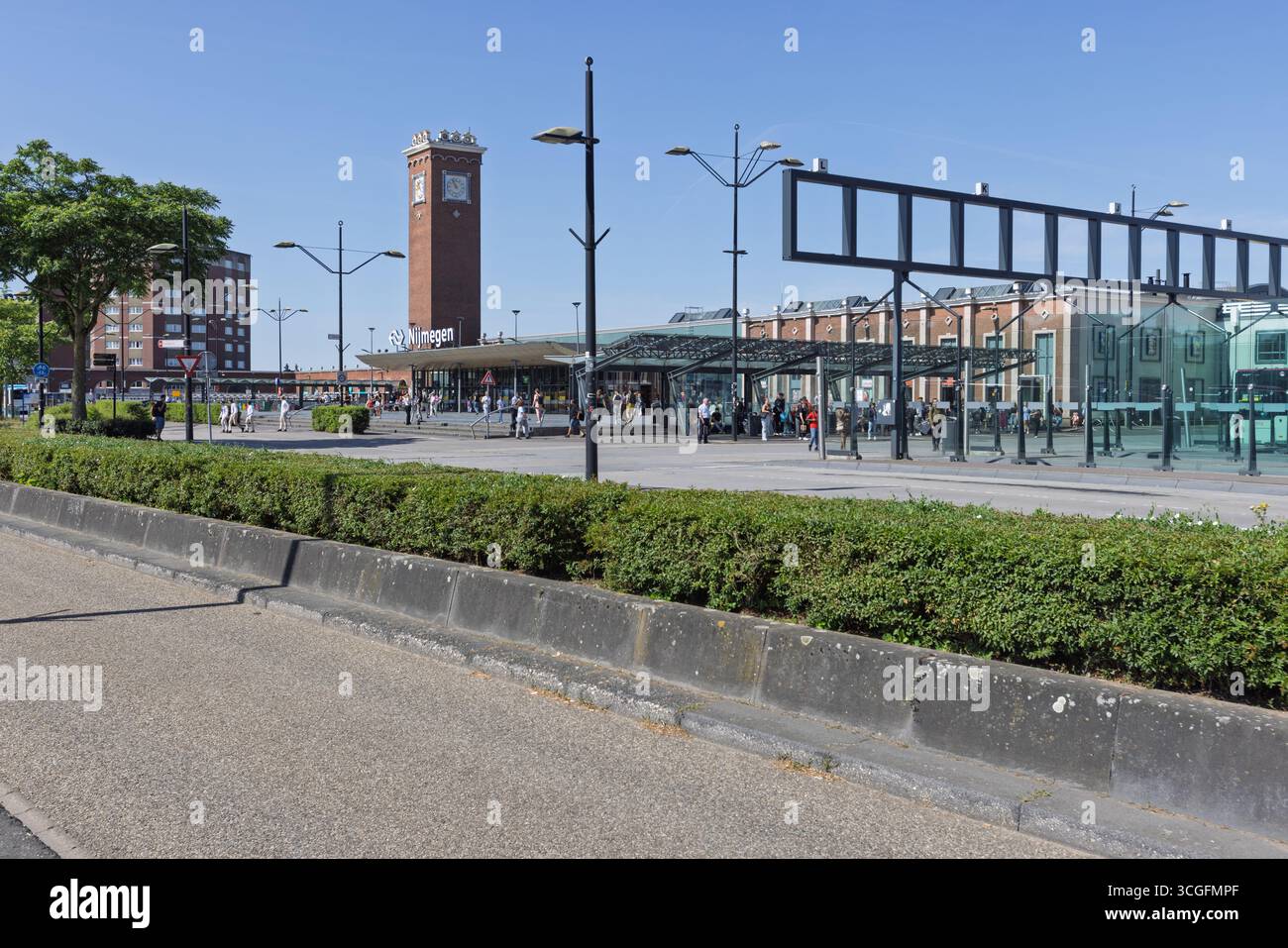 The main facade of Nijmegen Central Station, showing the clock tower and the new, glass-covered bus terminal on a bright day. Nijmegen, Netherlands. 2 Stock Photo