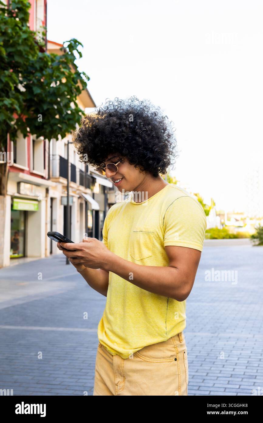 Young man using smartphone walking down the street Stock Photo