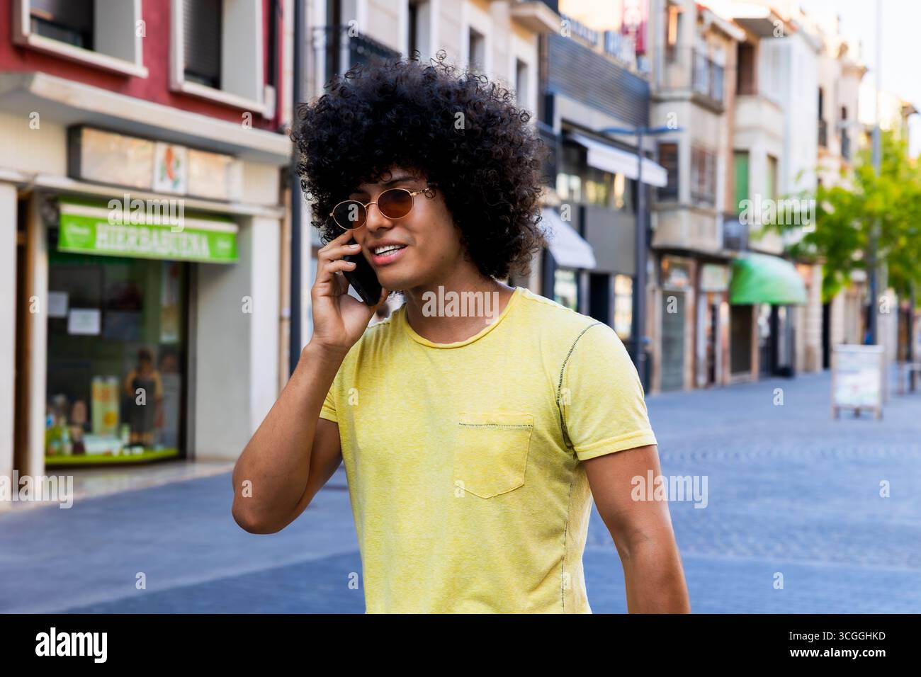 Young man walking down the street talking on smartphone Stock Photo