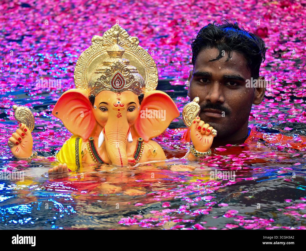 A volunteer carries an idol of the Hindu deity Ganesha for immersion in ...