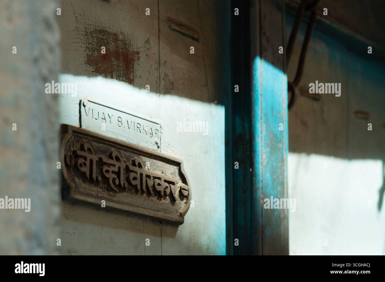 Blue wooden door with name written in devanagari and latin scripts in Pune, India. Stock Photo