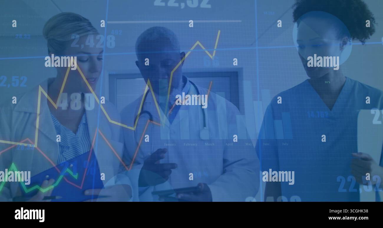 Analyzing medical team wearing coats, scrubs tapping tablets in clinic hallway, displaying charts Stock Photo