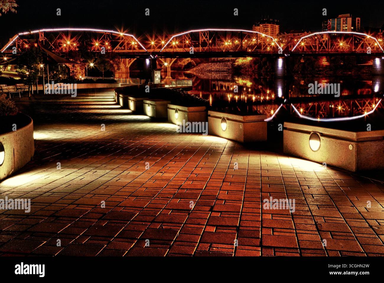 The Traffic Bridge illuminated after dark, casting reflections across the South Saskatchewan River in downtown Saskatoon. Stock Photo