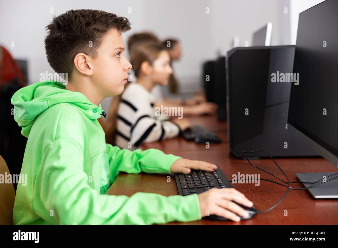 Focused tween boy studying with classmates in computer lab Stock Photo ...