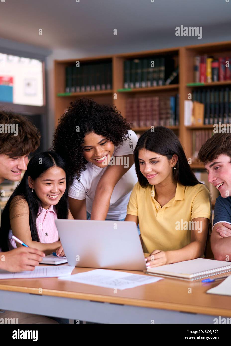 High school students collaborating on project in library using laptop Stock Photo