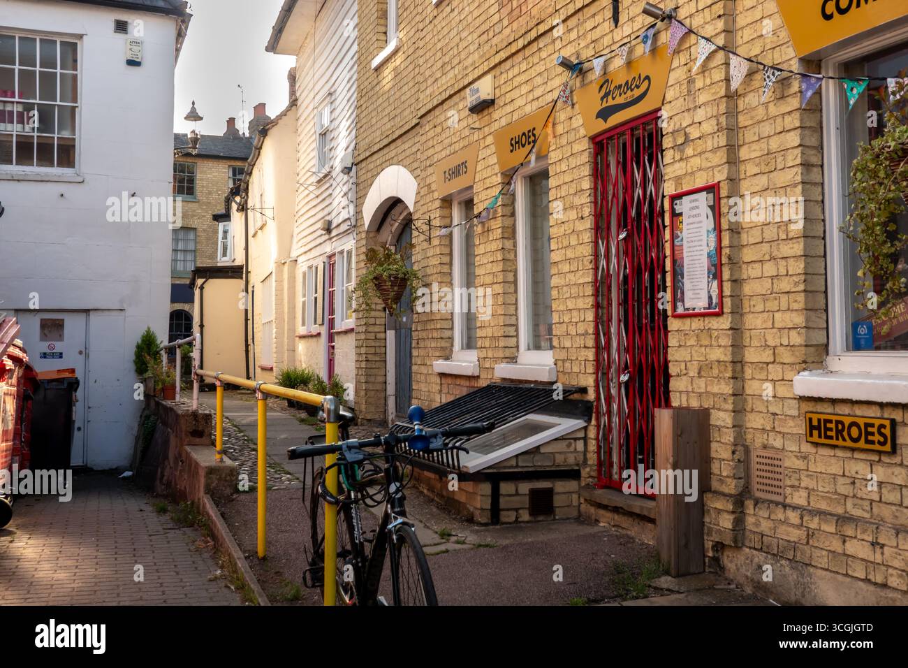 A narrow street scene in Saffron Walden, Essex, featuring brick buildings, a bicycle, and shops. Stock Photo