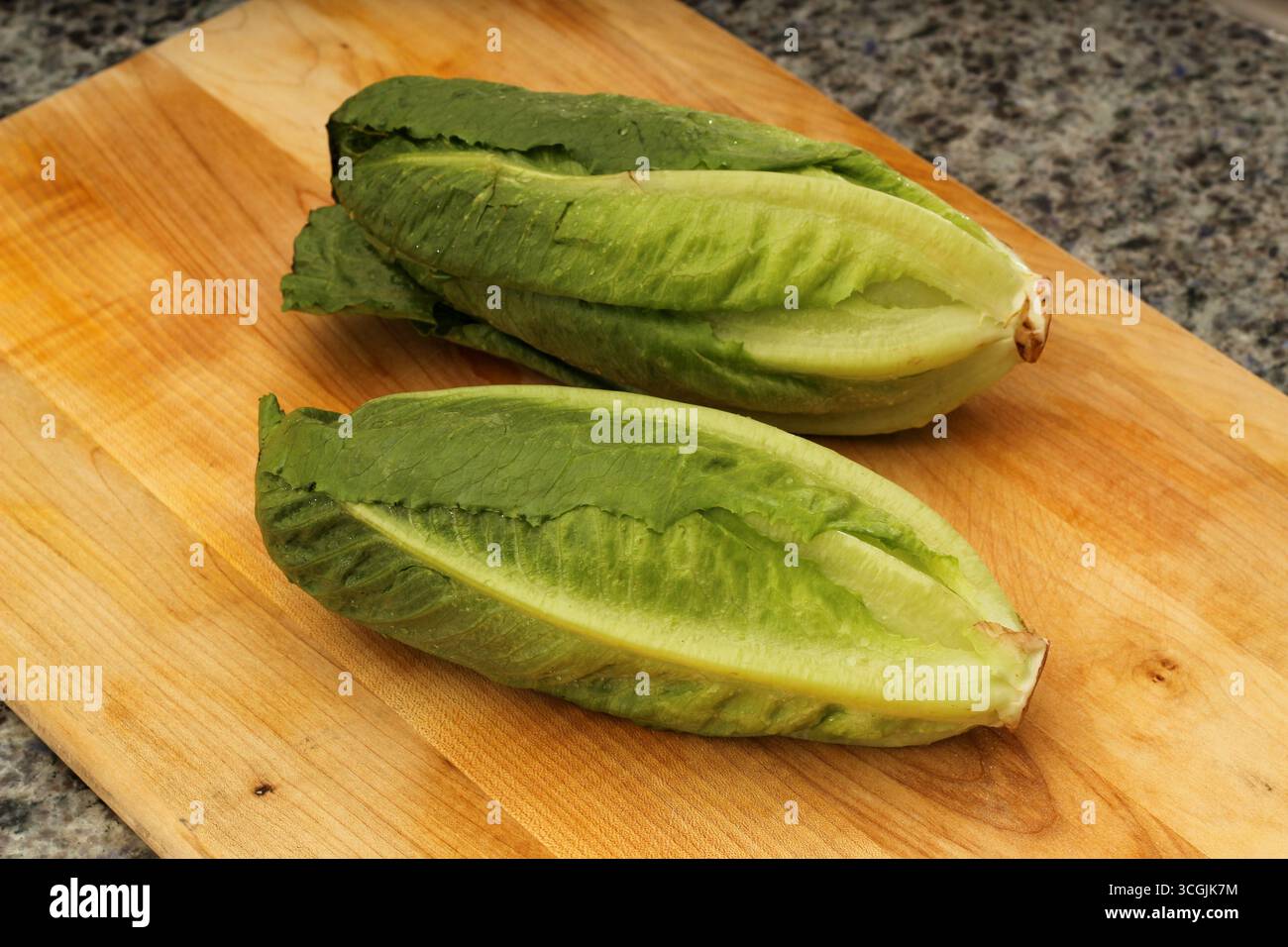 Two Romaine Lettuces on Wooden Cutting Board Stock Photo