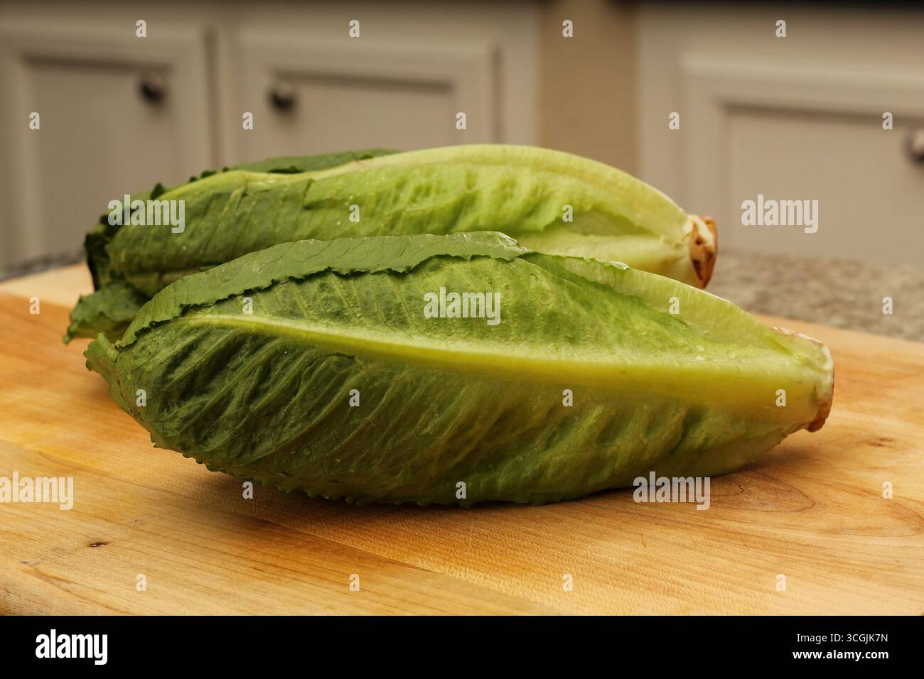Two Romaine Lettuces on Wooden Cutting Board Stock Photo