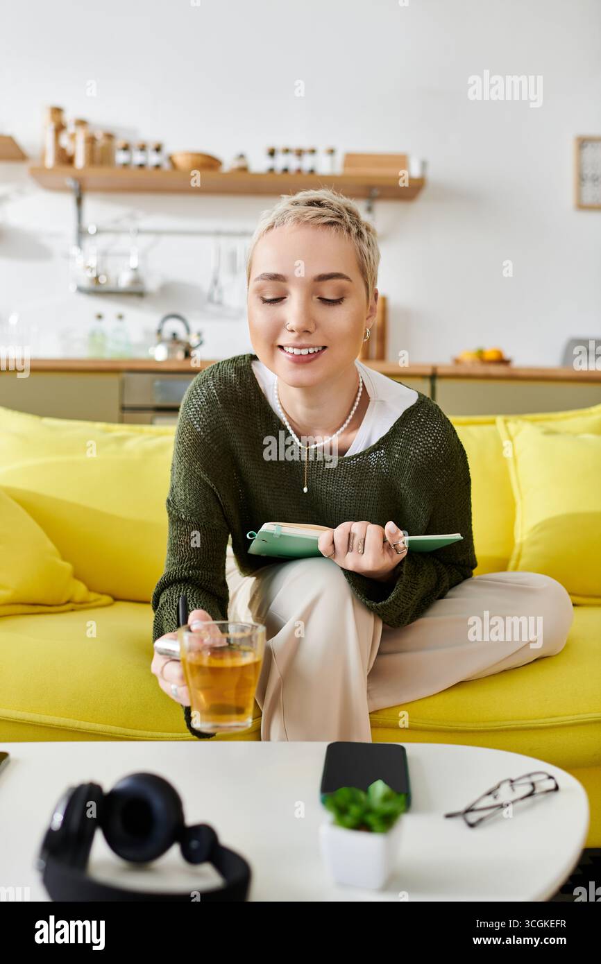 Relaxed atmosphere as a young woman sips tea while jotting down thoughts at home. Stock Photo