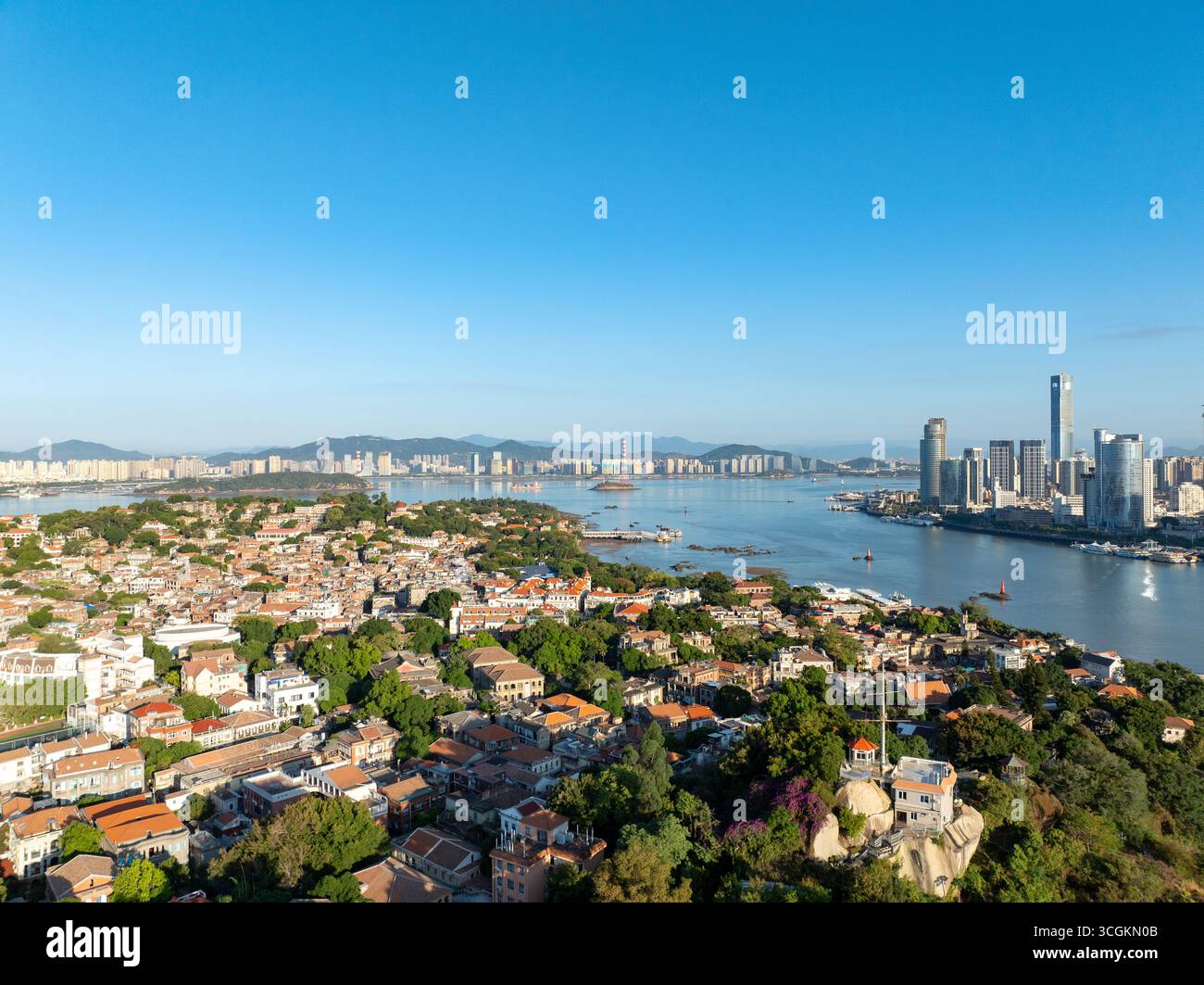 Panoramic view of the beautiful coastal city of Xiamen in China, showing modern skyscrapers, traditional buildings, and a bustling harbor. Stock Photo