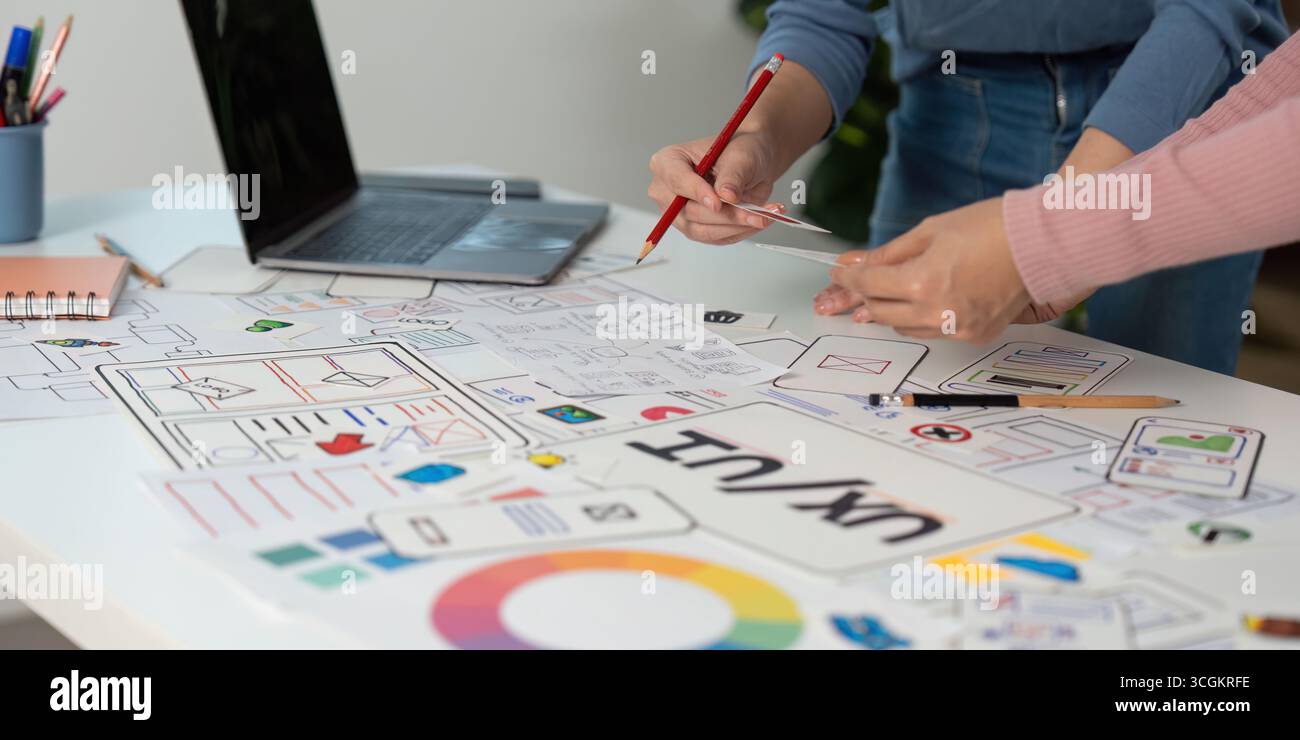 Creative UX and UI Design Process. Team members sketching and refining wireframes in a collaborative setting. Stock Photo