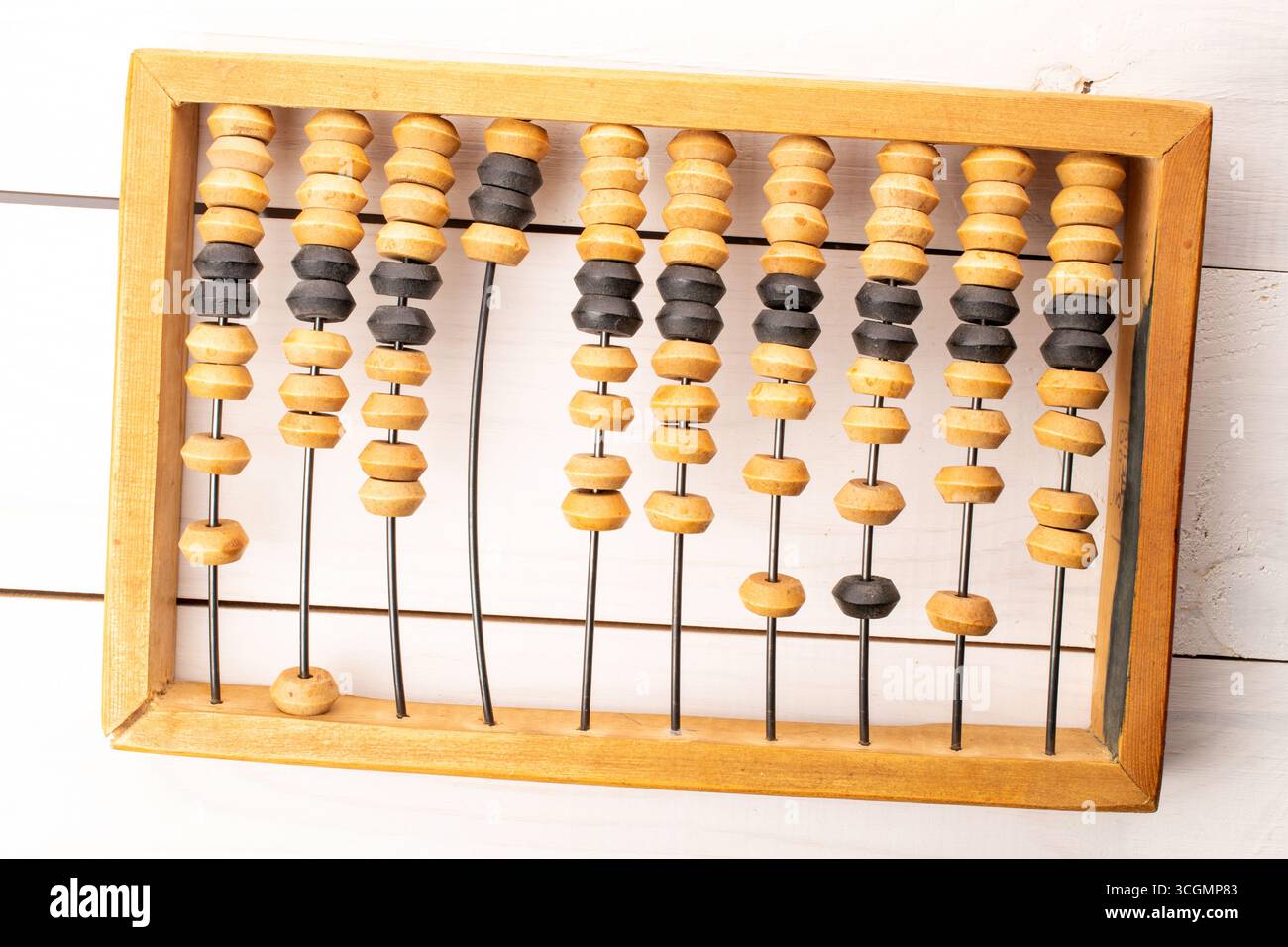 A calculator, which is a mechanical computing device for performing arithmetic operations, on a wooden table, close-up, top view. Stock Photo