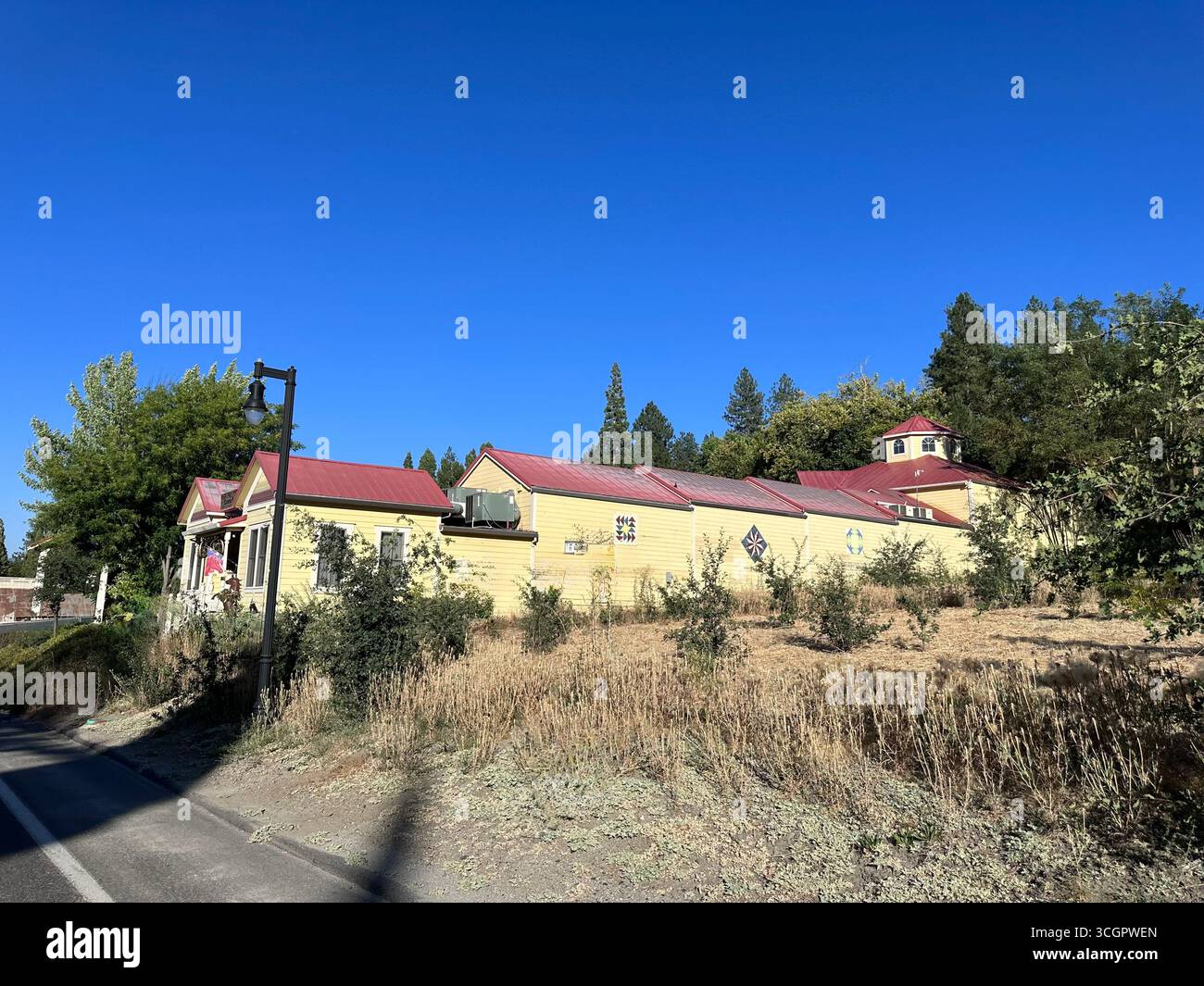 Historic Yellow Wooden Building with Red Roof and Cupola under Blue Sky - Smartphone Captured Stock Image
