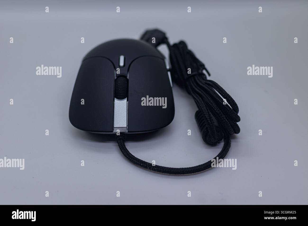 Modern Black USB Optical Mouse with Braided Cable on White Tabletop Background Stock Photo