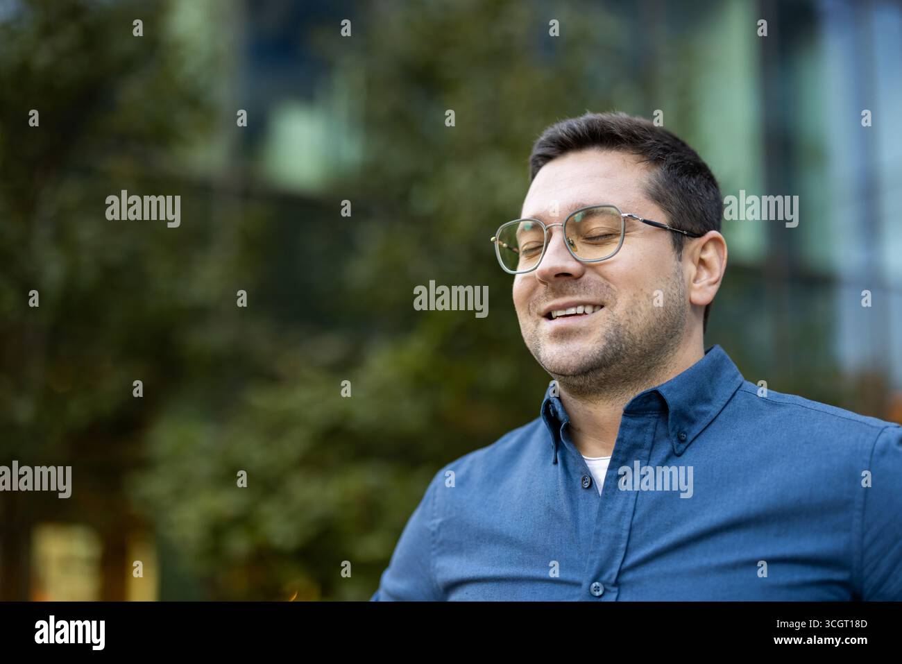 Young man in a serene setting closing his eyes, capturing a tranquil and joyful vibe. Stock Photo