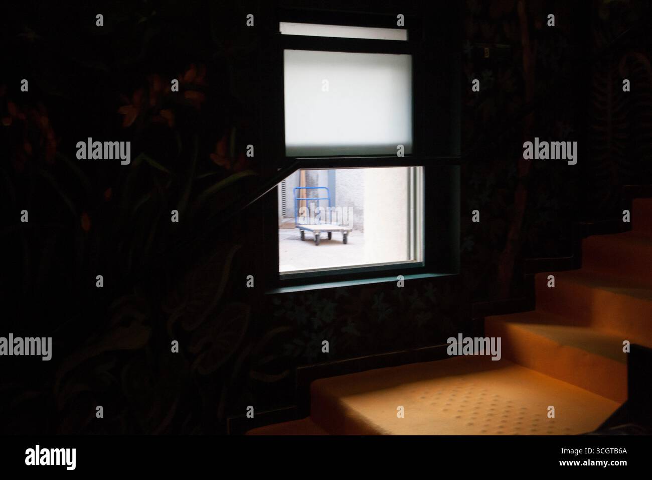 An open window with a trolley letting light in to a dark staircase ...