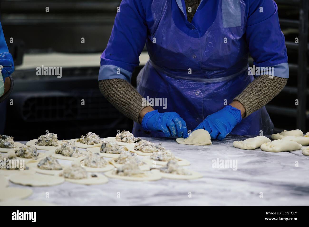 Baker kneading dough and making pies at bakery Stock Photo