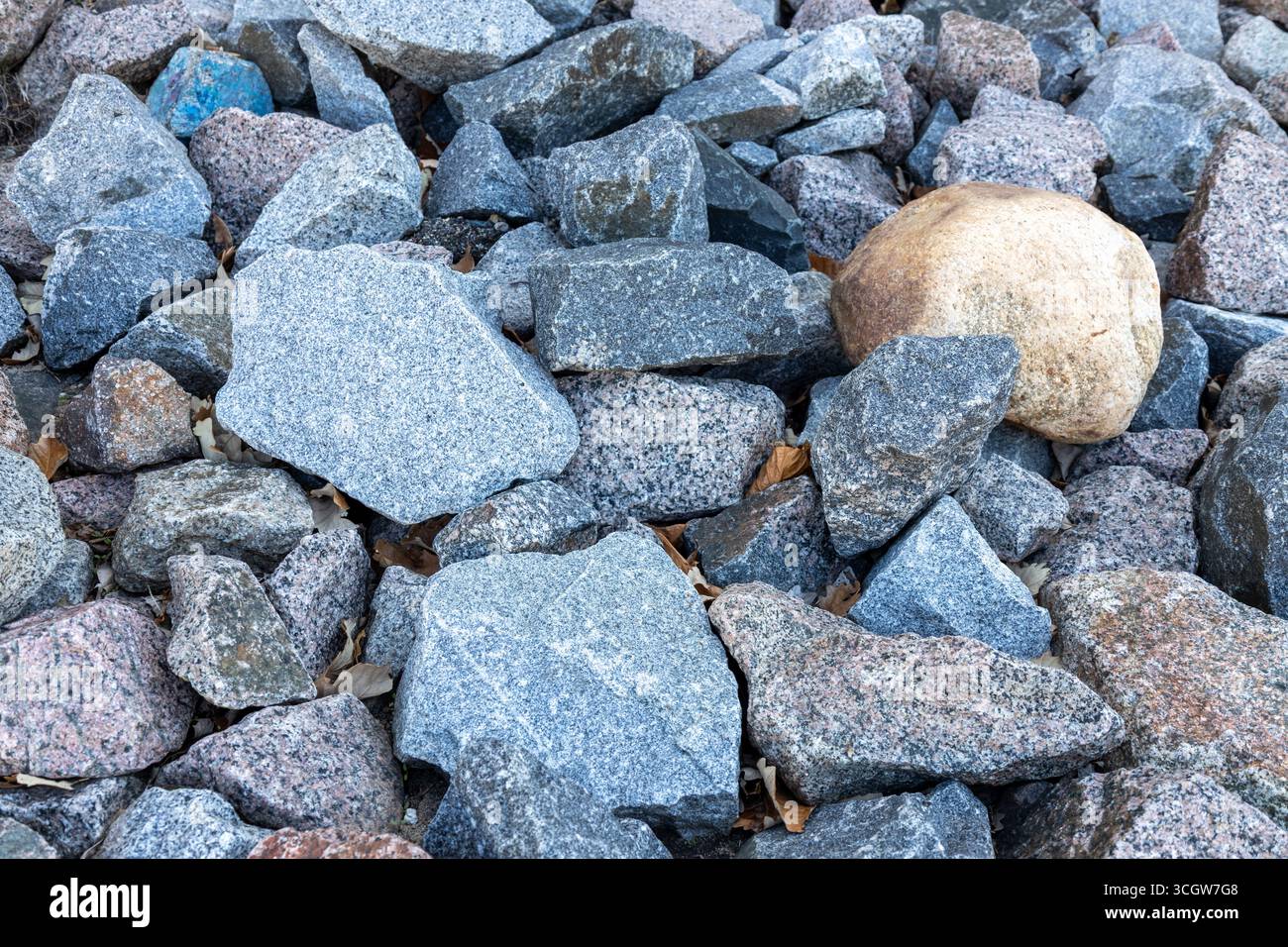 Abstract texture background view of a pile of multicolor natural granite stone rocks in natural condition Stock Photo