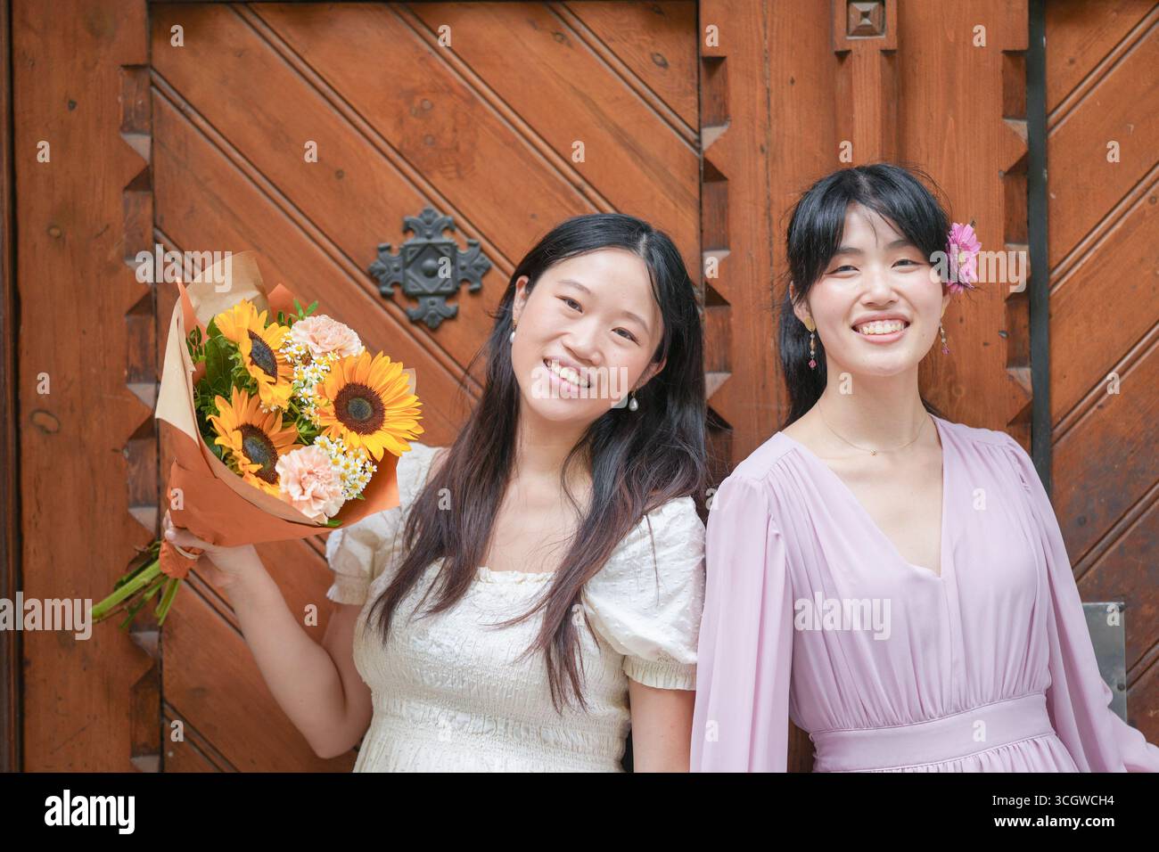 Two women are posing for a picture, one of them holding a bouquet of ...
