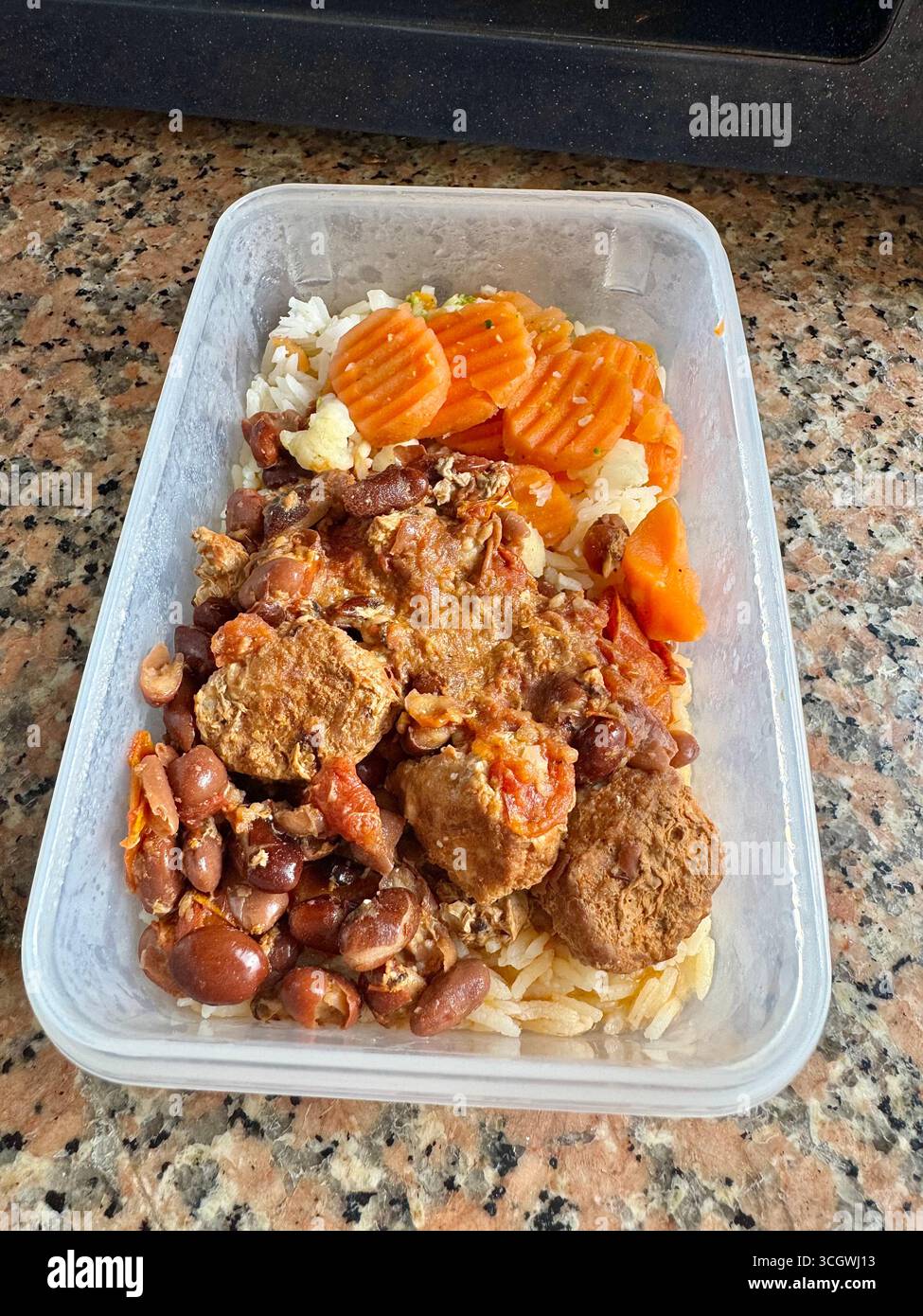 Healthy meal prep with rice, beans, almonds, vegetables, and protein in a container ready for microwave. - Smartphone Captured Stock Image