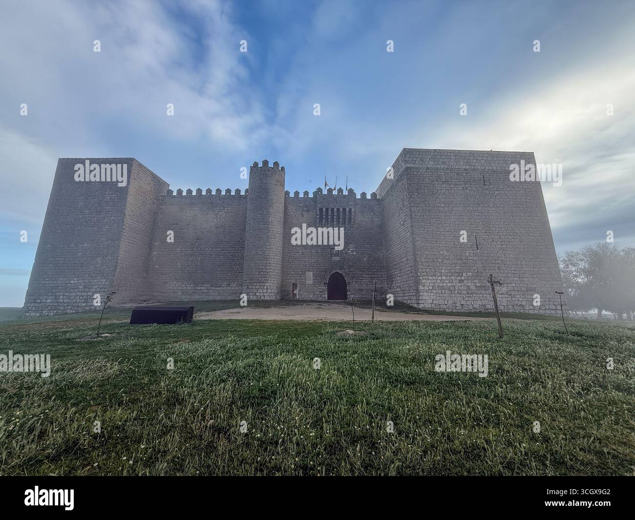 Imposing stone fortress surrounded by mist, featuring battlements and ...