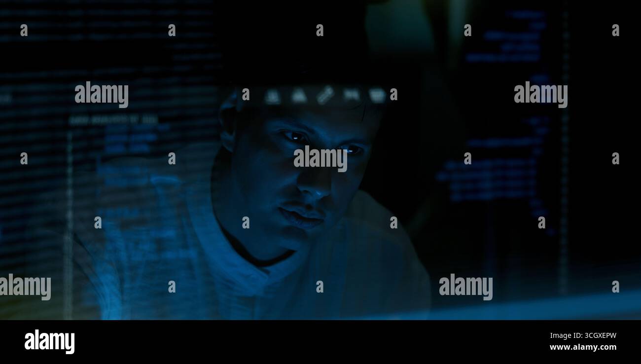 Programmers and coding. Programmer or Developer working in dark room with computer code reflected on their monitor. Cybersecurity software development Stock Photo