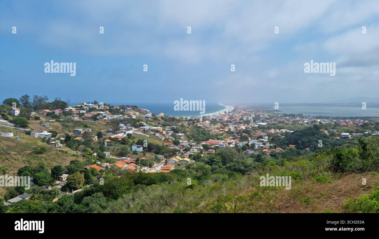 A wide coastal town unfolds gently between green hills and the ocean - Smartphone Captured Stock Image