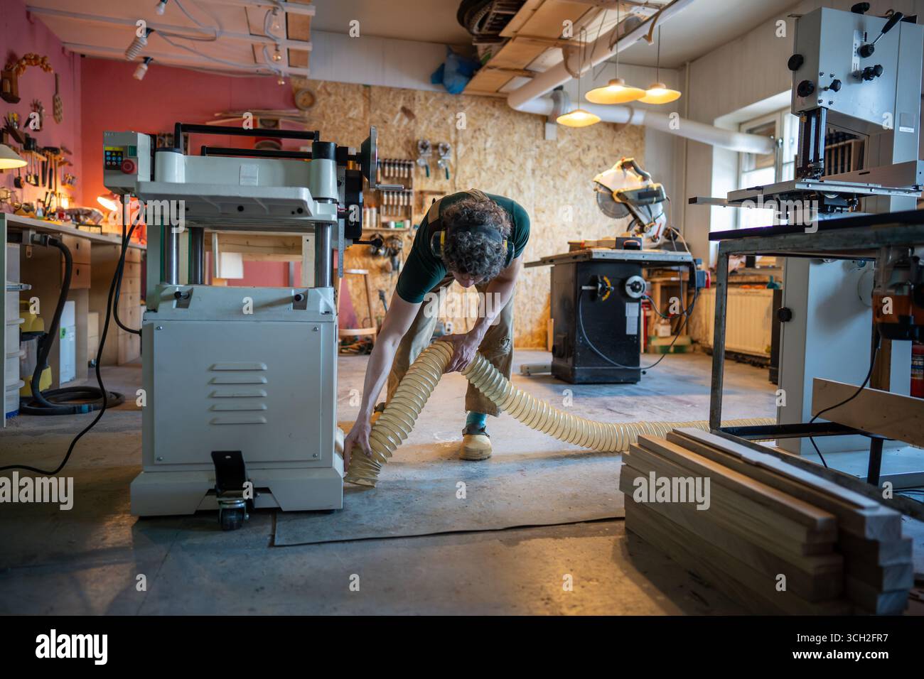 Focused busy carpenter woodworker clean floor with industrial vacuum ...