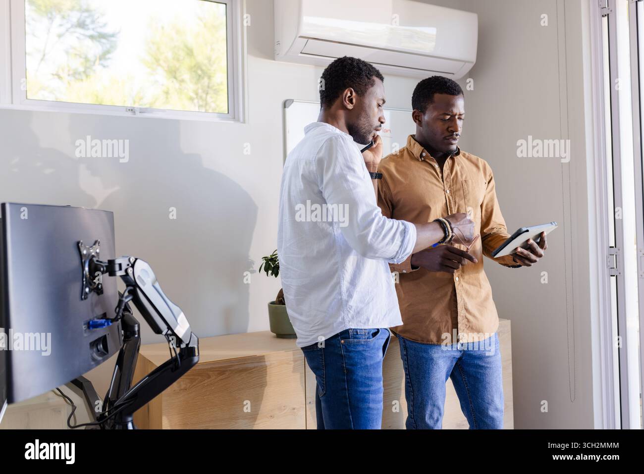 Two men discussing project details while using tablet in modern office Stock Photo