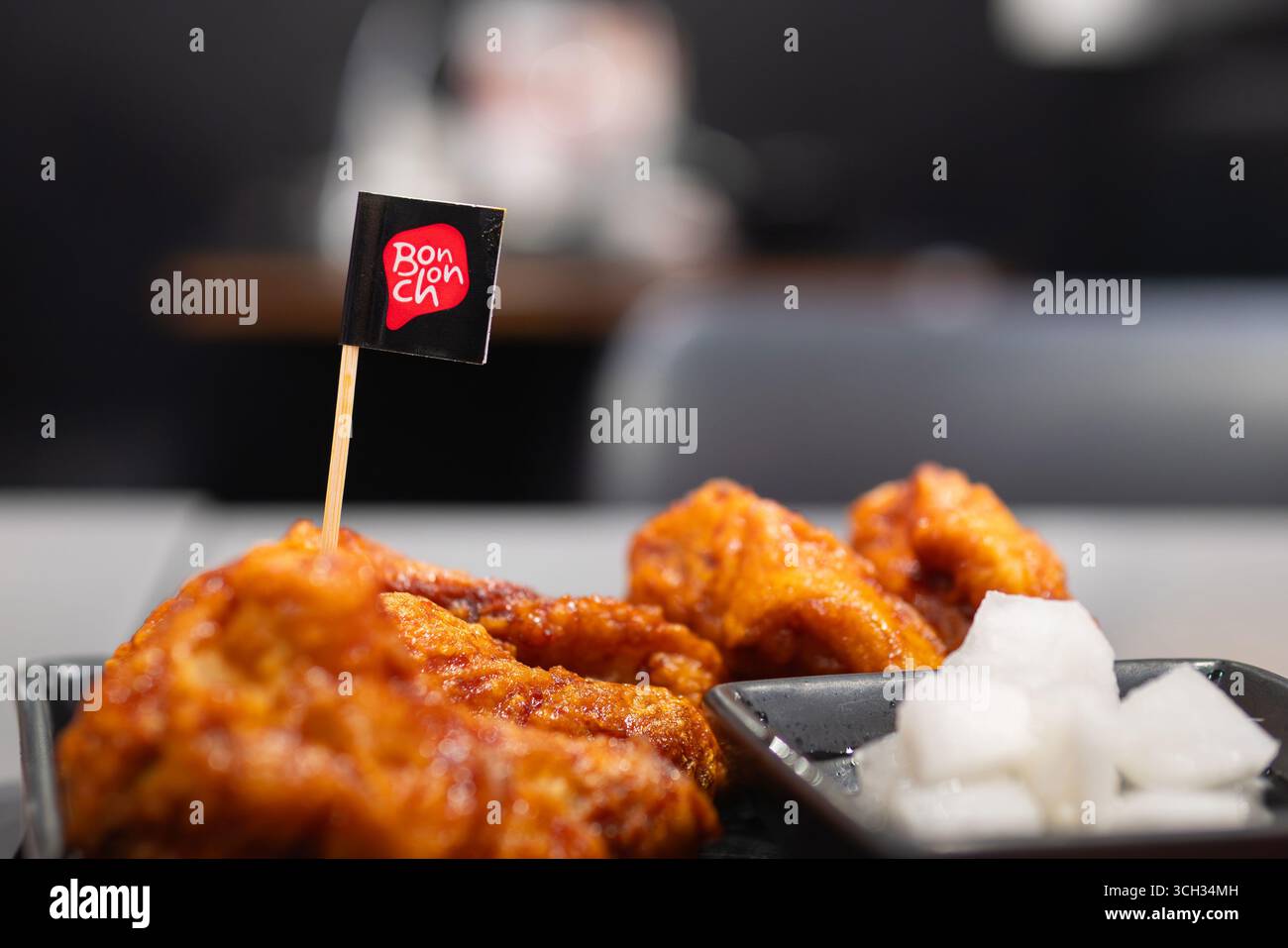 Bangkok, Thailand - August 23, 2025: Crispy Korean Fried Chicken on a dish with a decorated flag of Bonchon, a Korean food restaurant. Stock Photo