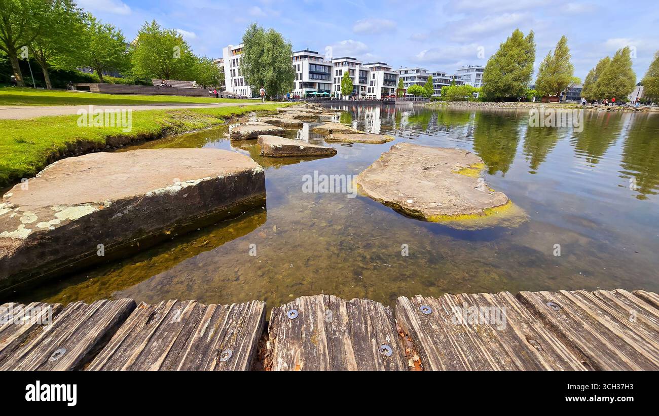 Phoenix see Dortmund landscape villas and the lake view. Phoenix See in Dortmund features a serene lake with large, flat rocks emerging from the water Stock Photo