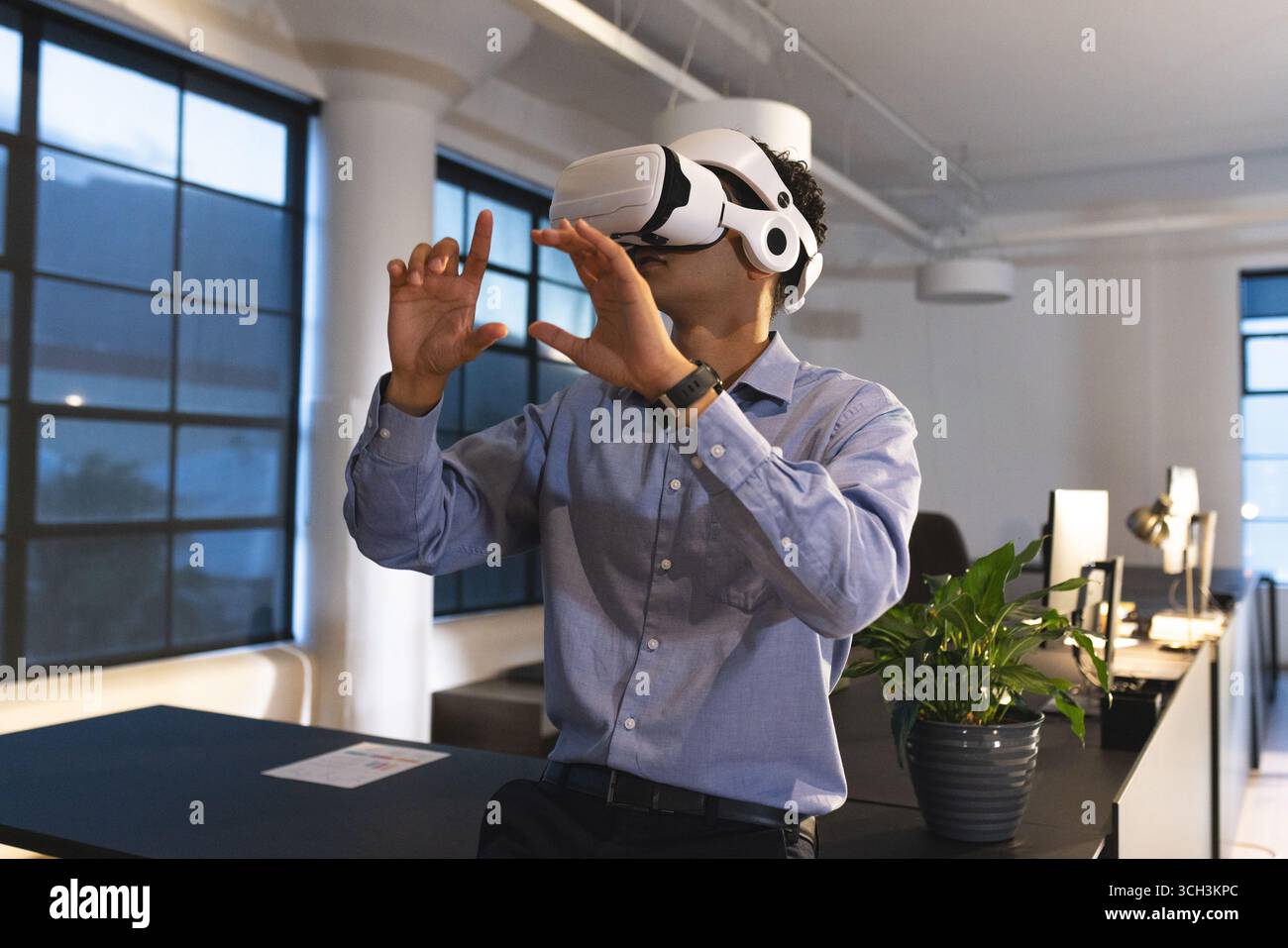 Businessman using VR headset in modern office, exploring virtual environment Stock Photo